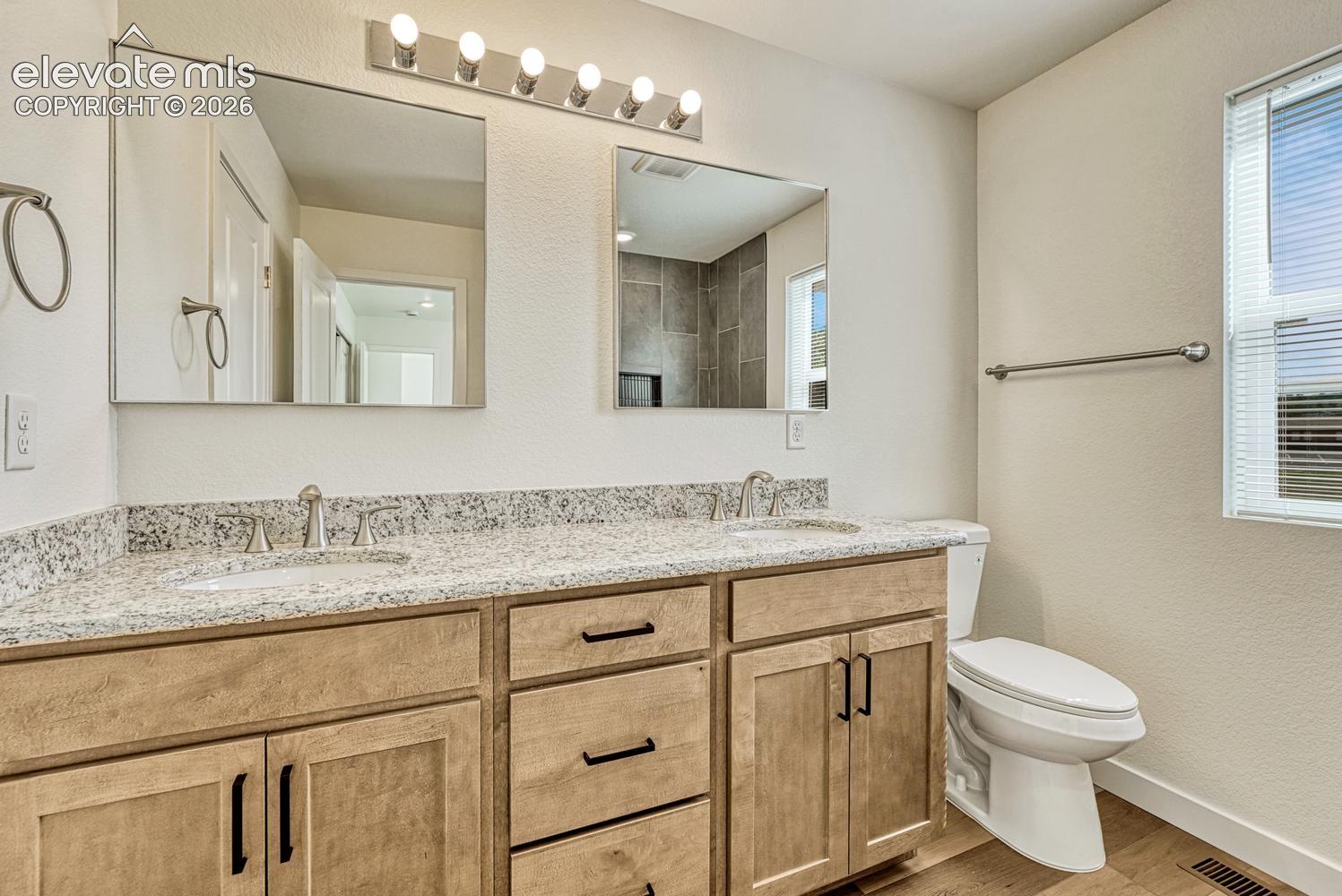 Jack-and-Jill bathroom with double vanity, granite counter, and undermount sinks