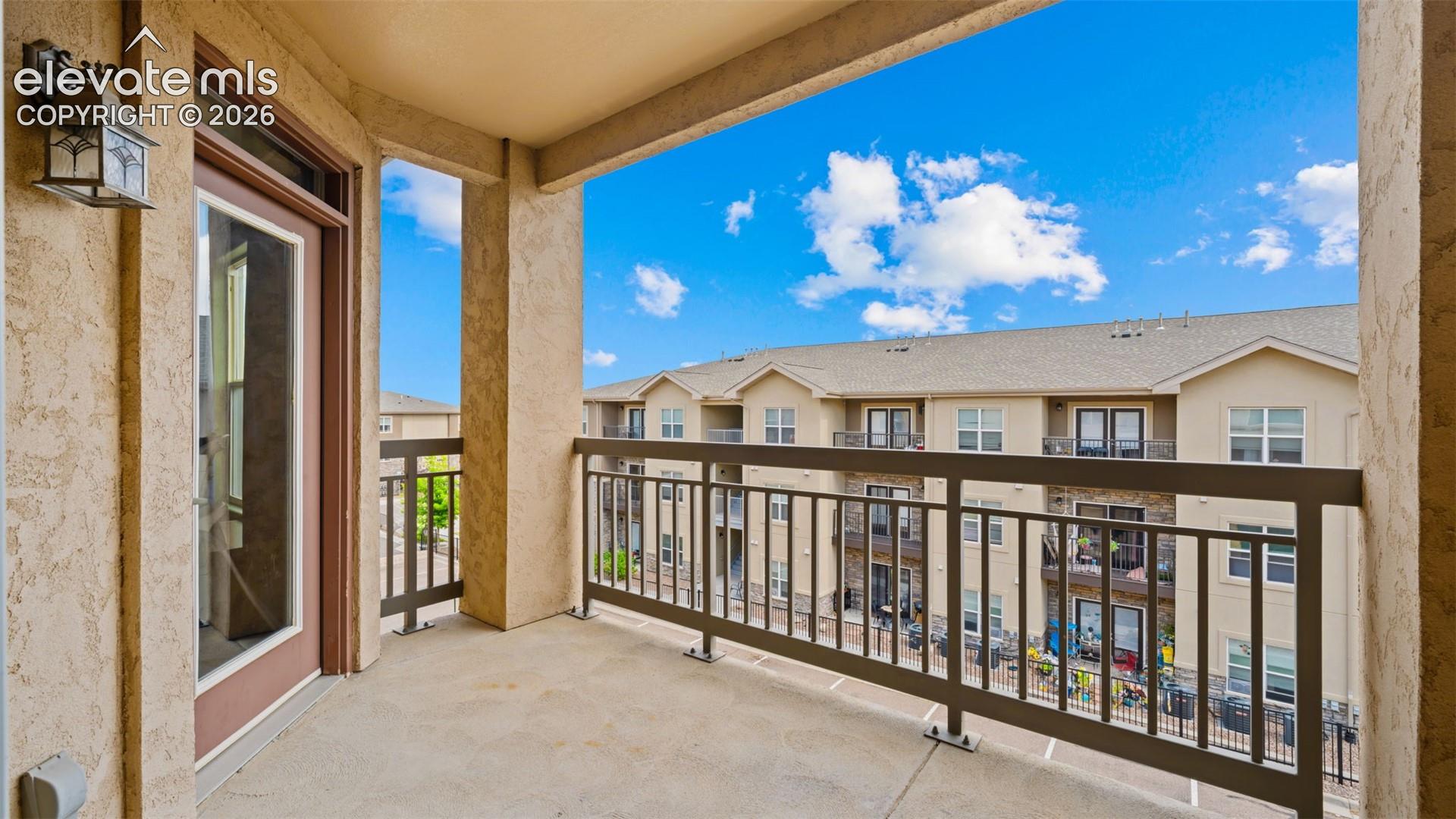 Private balcony featuring a concrete floor, stucco walls, and a dark metal railing