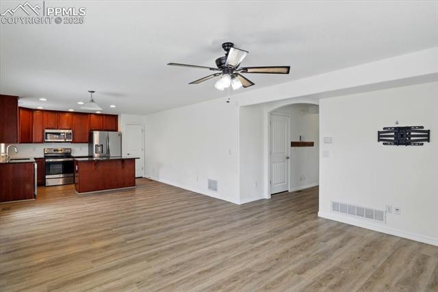 Kitchen with appliances with stainless steel finishes, open floor plan, recessed lighting, a center island, and dark countertops