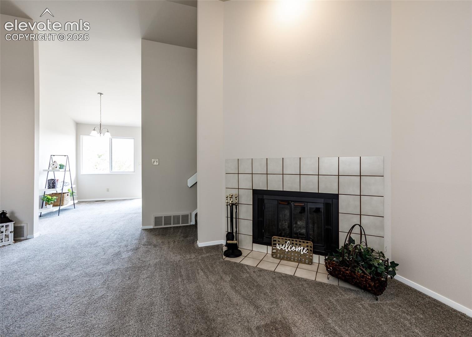 Carpeted flooring throughout, with an integrated fireplace featuring a tile surround and hearth