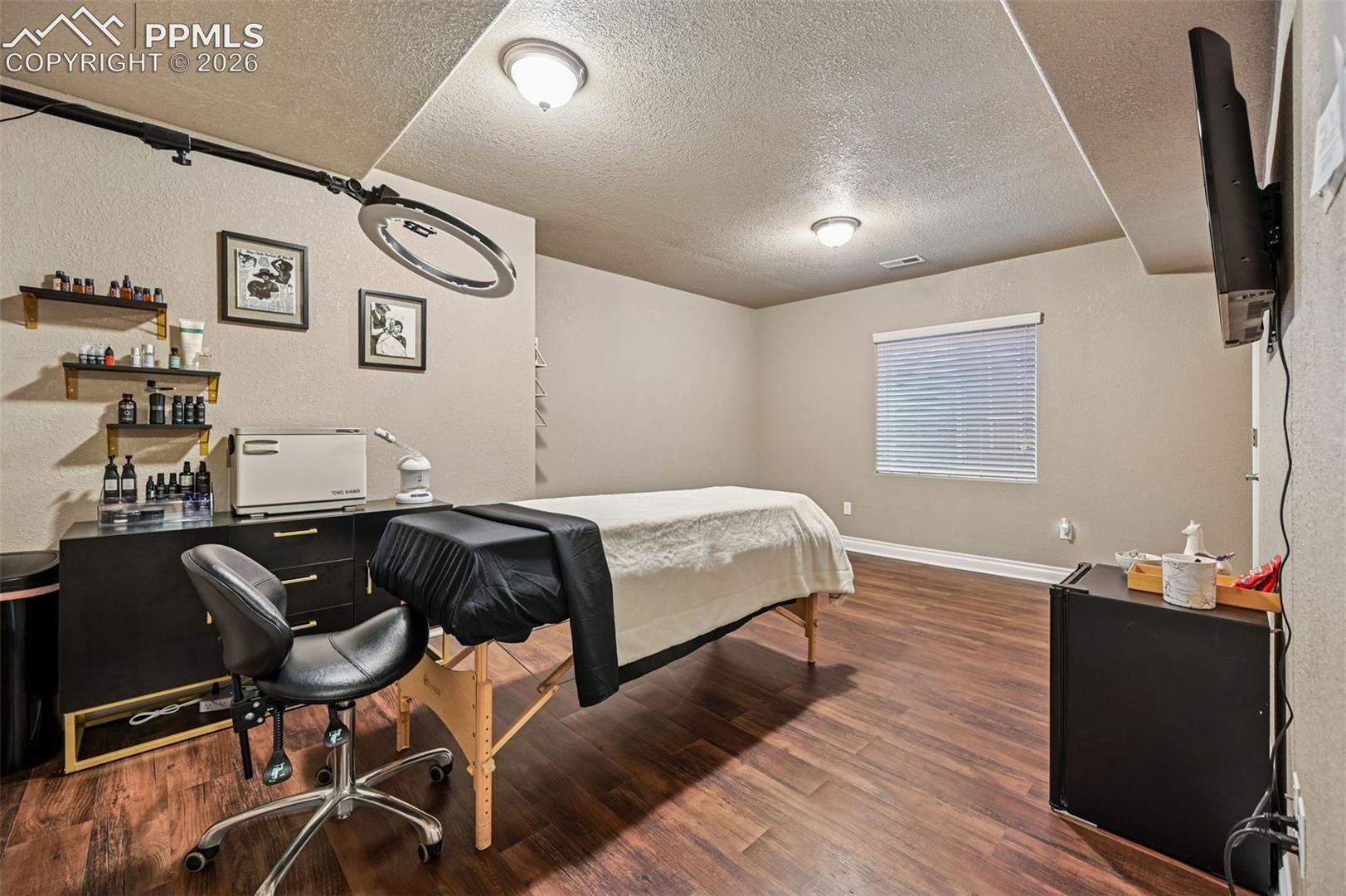 Bedroom featuring a textured ceiling, dark wood-style floors, and a textured wall
