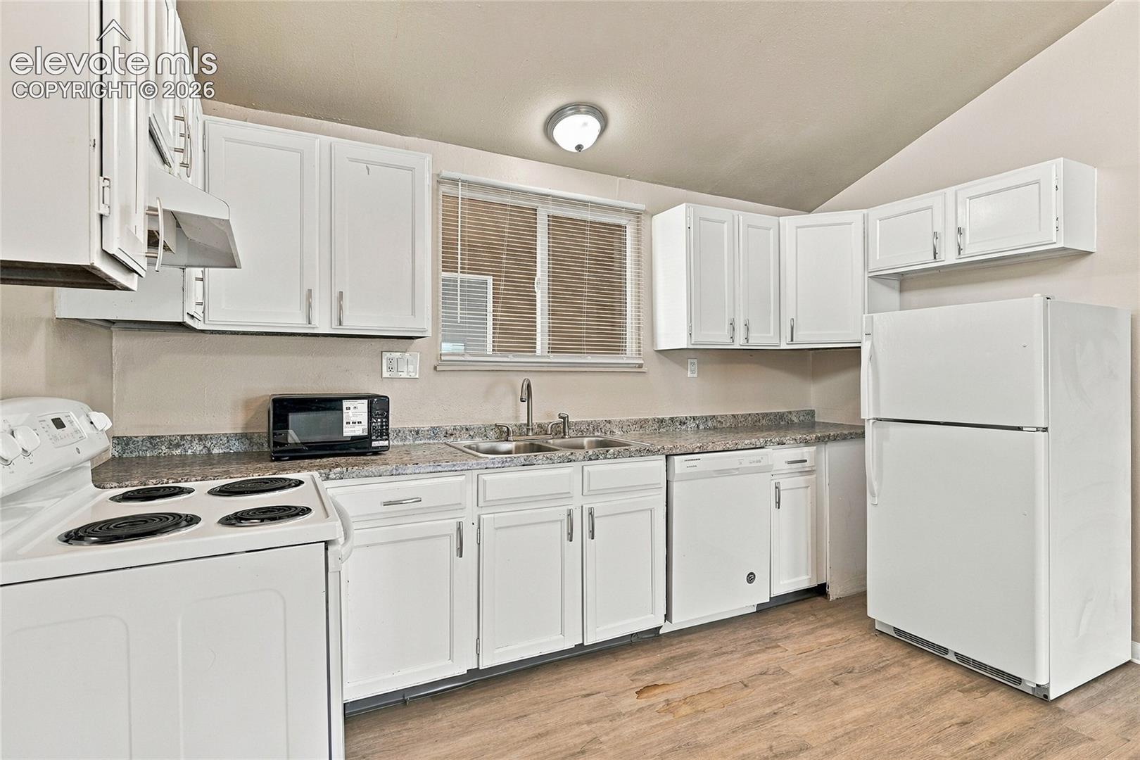 Kitchen featuring white cabinetry, stone-finish countertops, stainless steel dual-basin sink, and wood-finish flooring