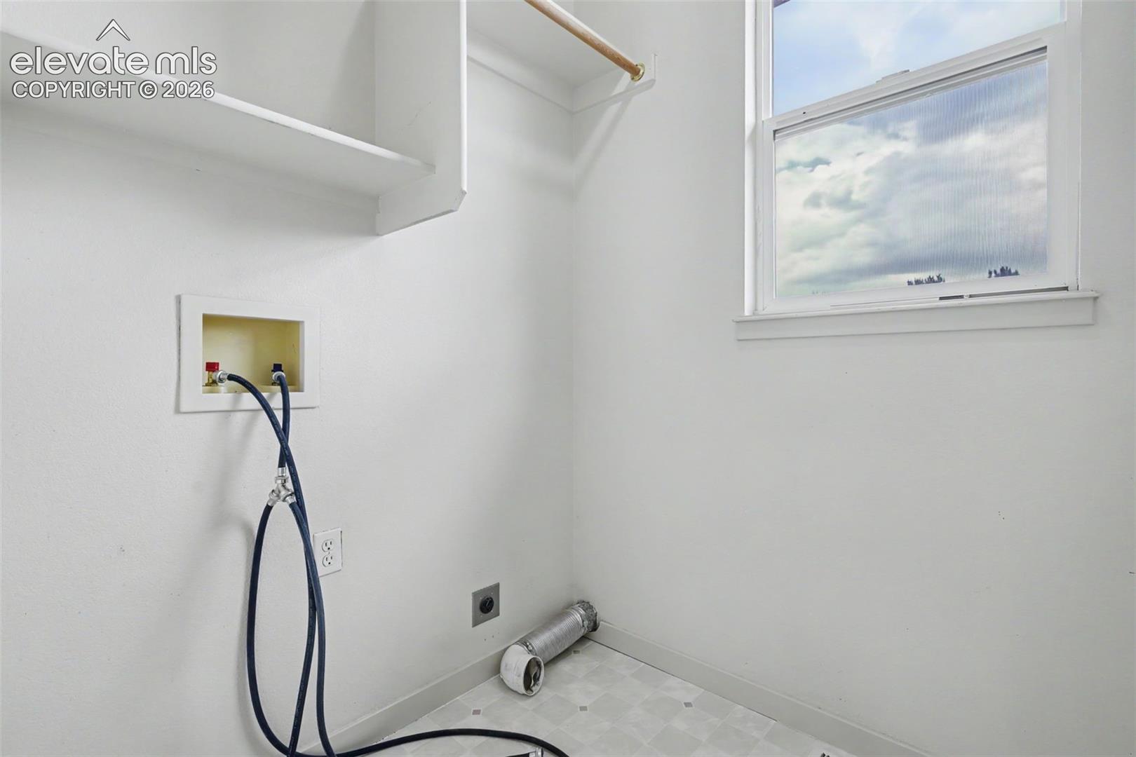 Dedicated utility space featuring a single window, overhead shelving, and a wooden hanging rod