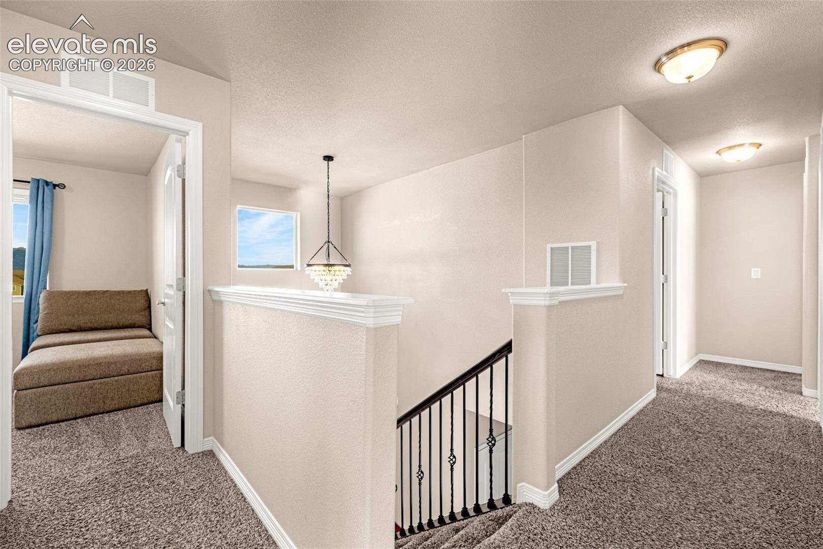 Carpeted hallway with a decorative chandelier, recessed lighting, and a window