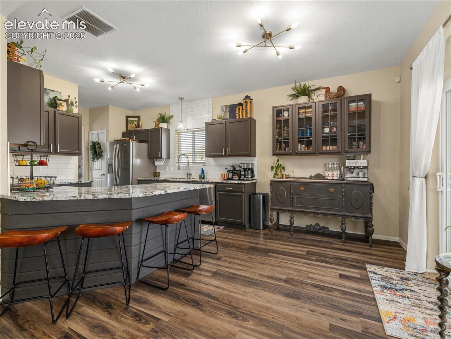 Kitchen featuring LVP flooring, dark cabinetry, and a central island with a speckled countertop