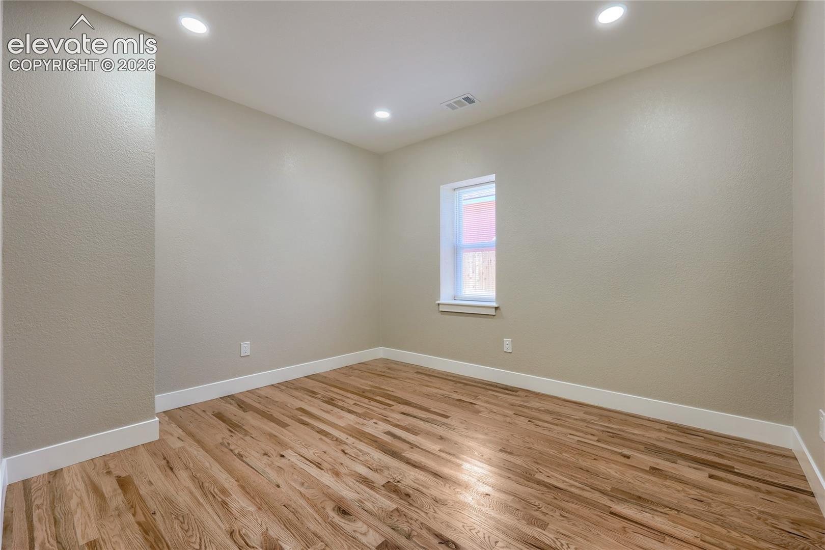 A generous-sized third bedroom features soft natural light, hardwood flooring, and a double-slider door to a spacious reach-in closet. This room also offers easy access to the main hall bath.