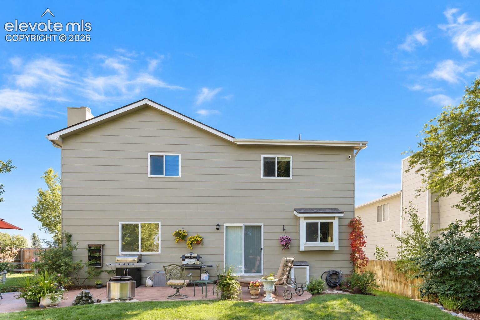 Rear view of home and fenced backyard with a concrete patio for outdoor dining and relaxation.