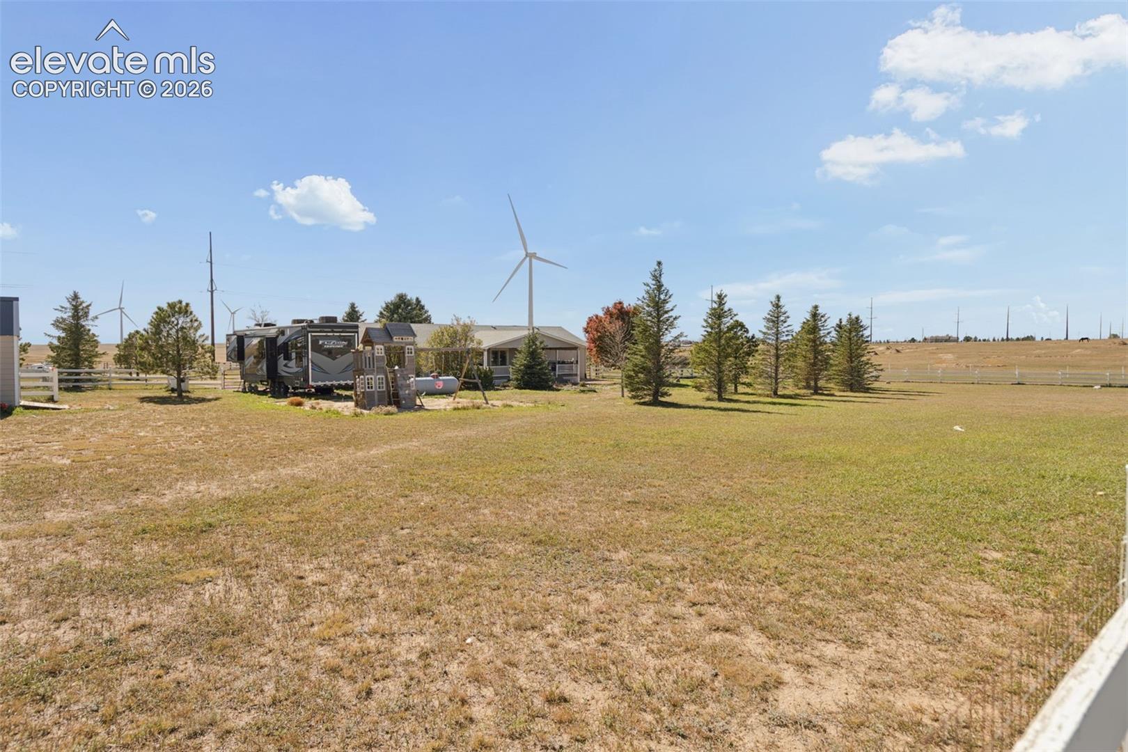 Expansive acreage featuring mature evergreen trees, white rail fencing, and open space
