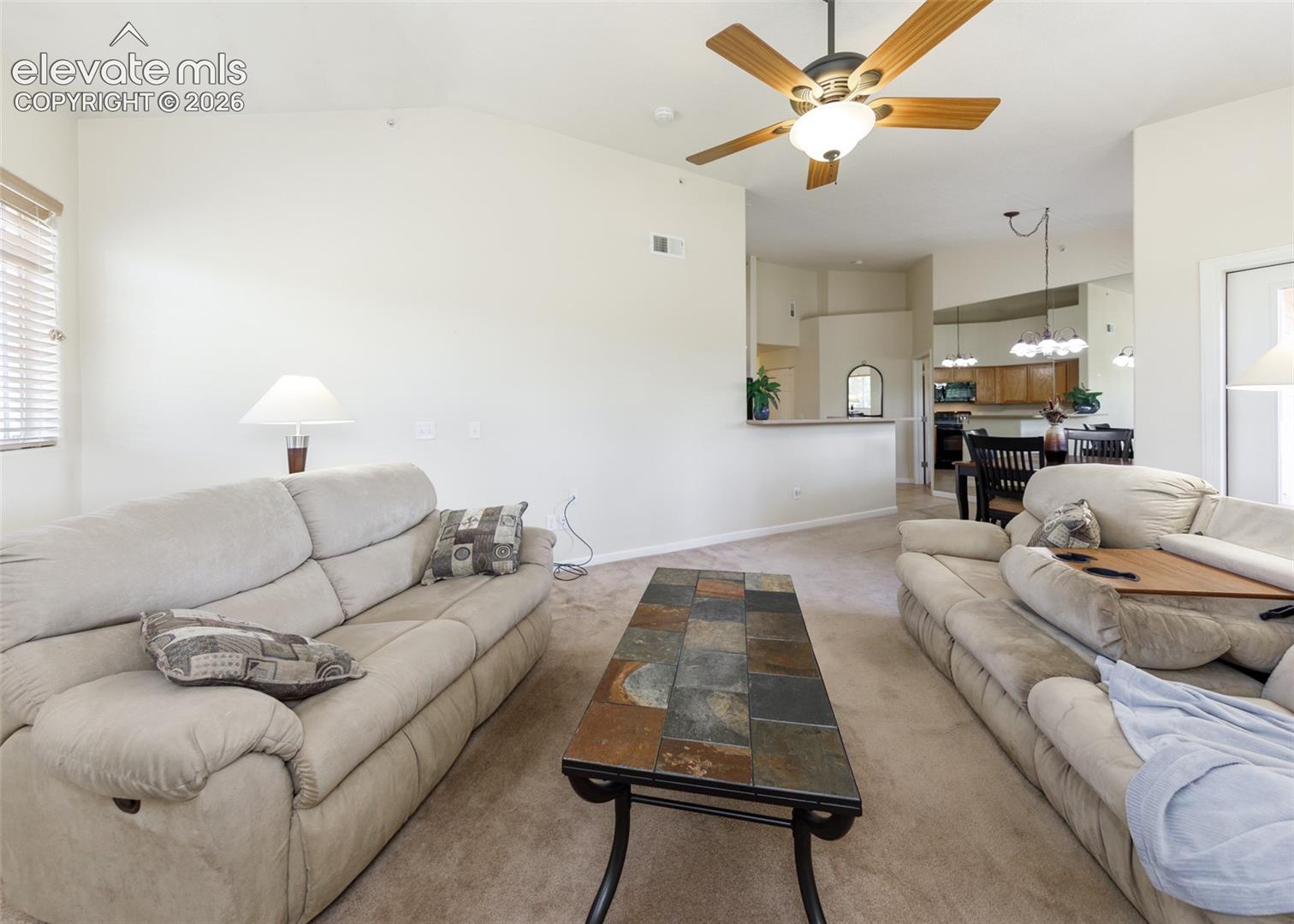 Vaulted ceiling featuring a central multi-blade ceiling fan with integrated light fixture