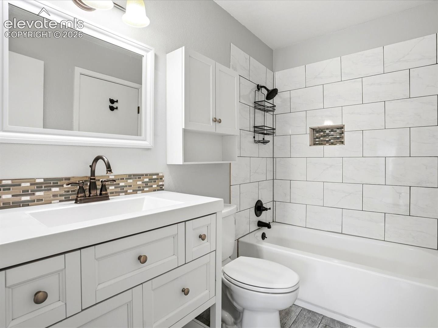 White vanity featuring a solid surface countertop, rectangular undermount sink, and bronze-finish hardware