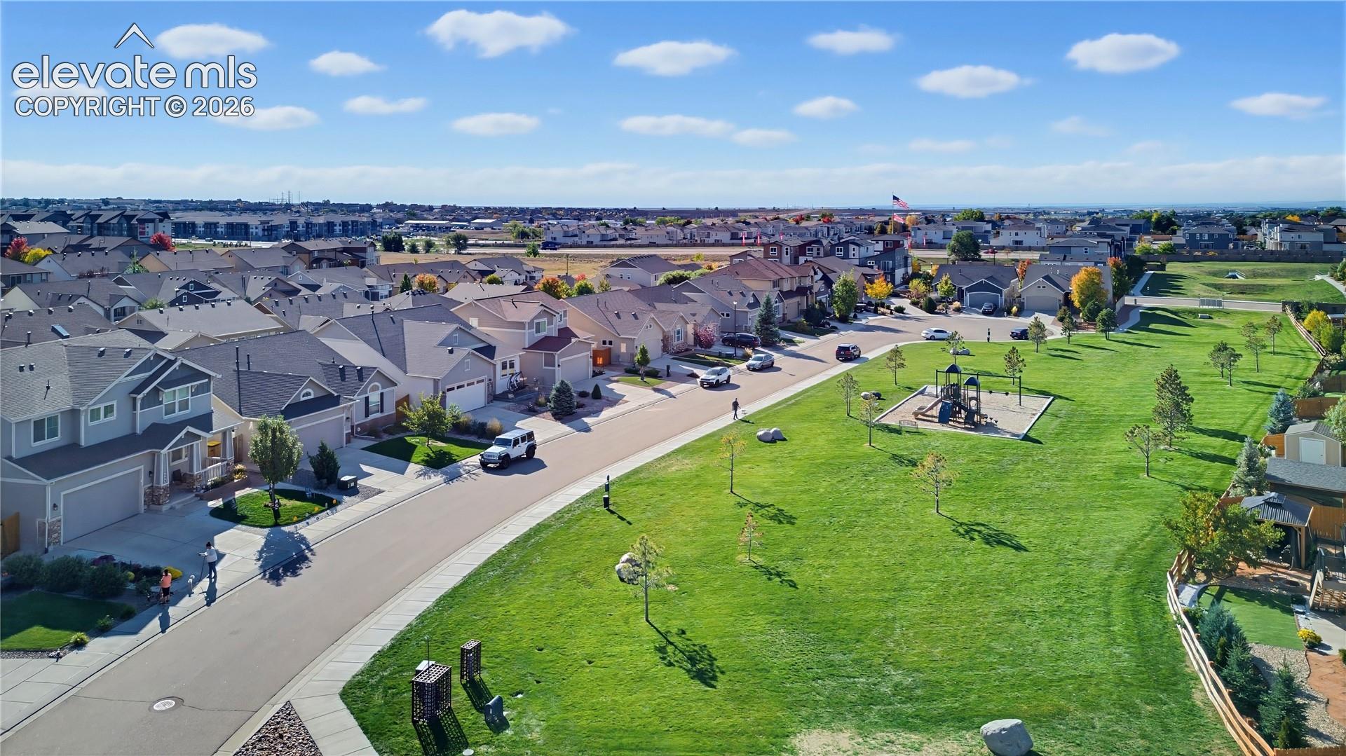 Aerial perspective featuring expansive manicured green space, paved street infrastructure, and established residential landscaping
