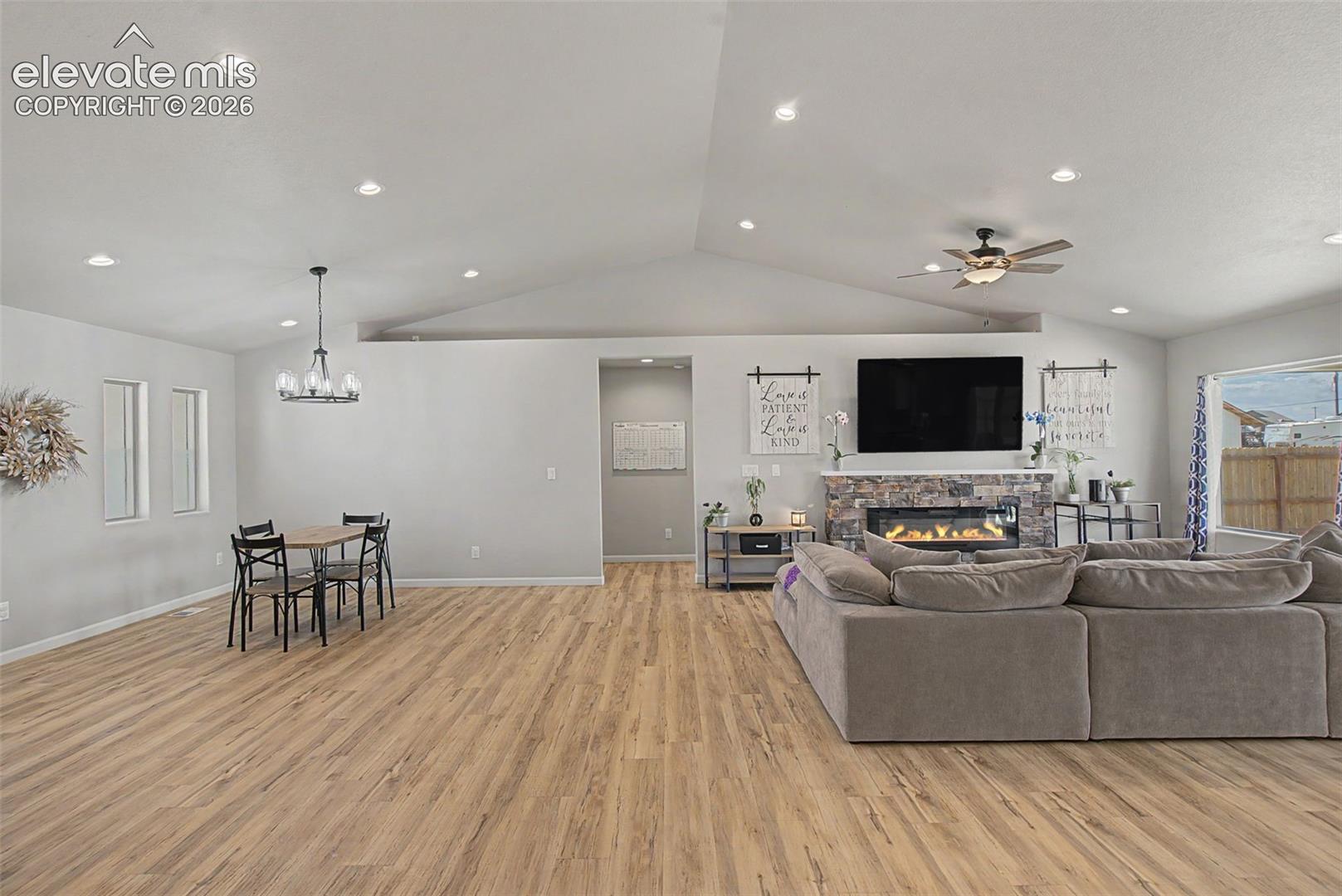 Spacious living area featuring vaulted ceilings, recessed lighting, and wood-finish flooring