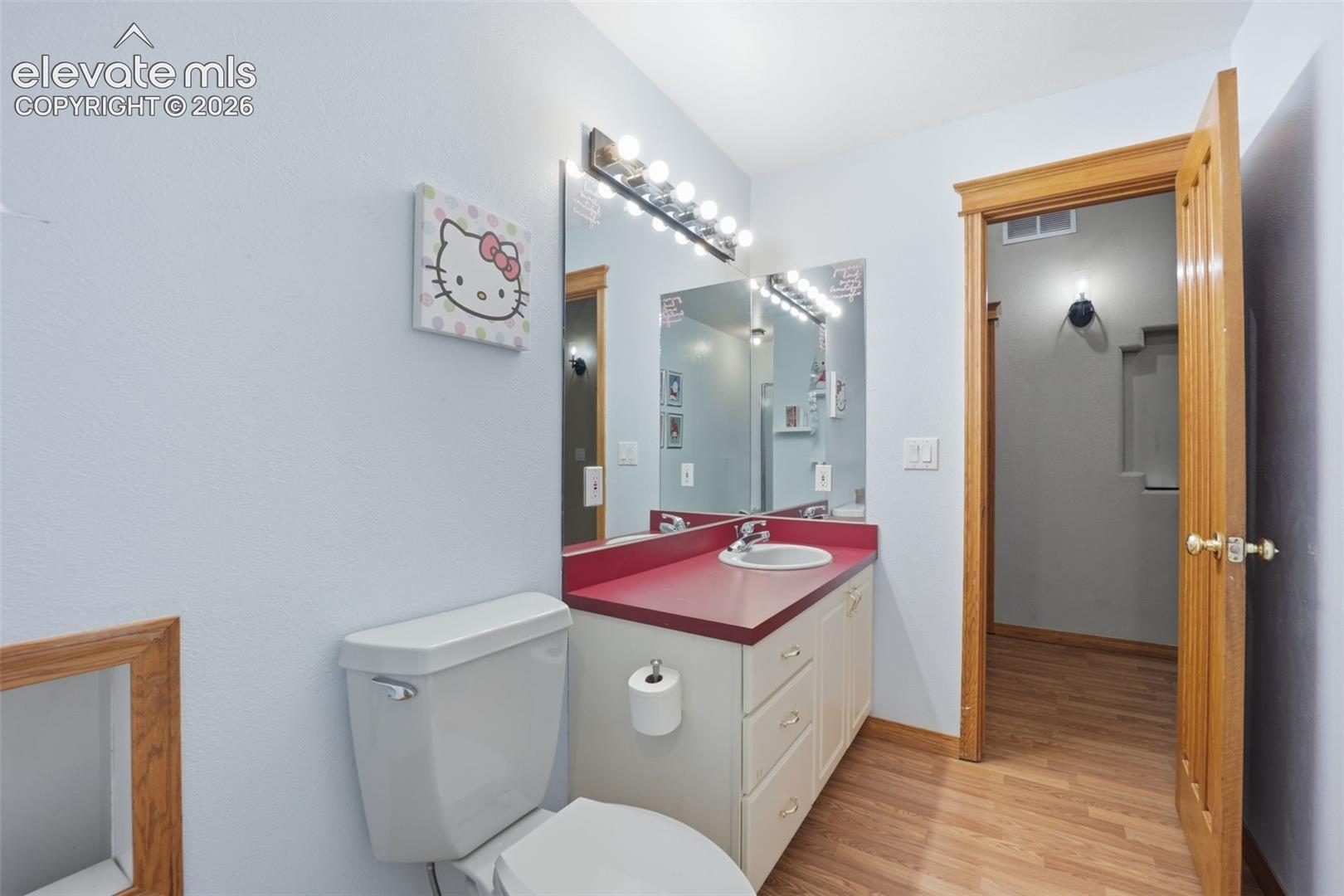 Bathroom featuring a single vanity with a red countertop, integrated sink, and white cabinetry