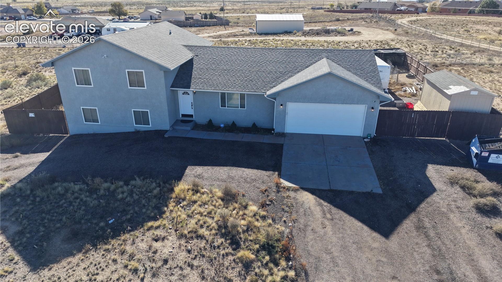 Residence featuring a stucco exterior, asphalt shingle roof, attached garage, concrete driveway, and enclosed wood fencing