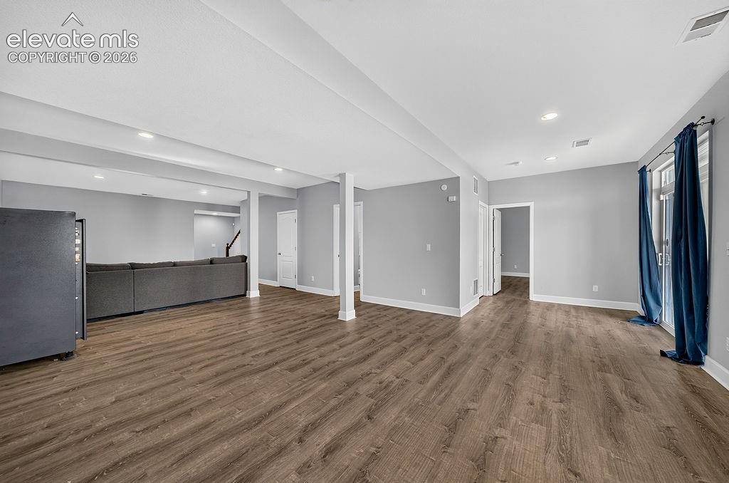 Spacious room featuring wood-finish flooring, recessed lighting, and light grey walls
