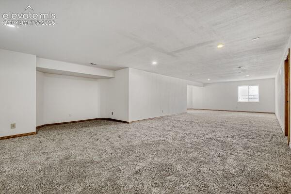 Expansive interior space featuring light gray textured carpeting, white painted walls, and recessed ceiling lighting