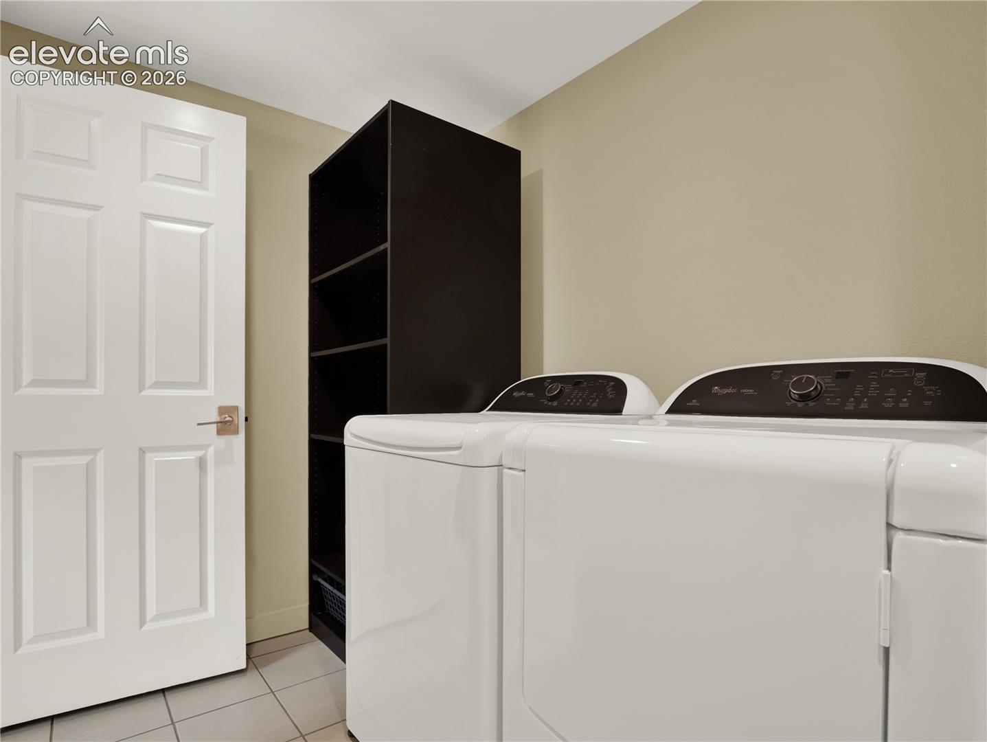 Six-panel interior door with brushed metal hardware, built-in shelving unit, and tile flooring