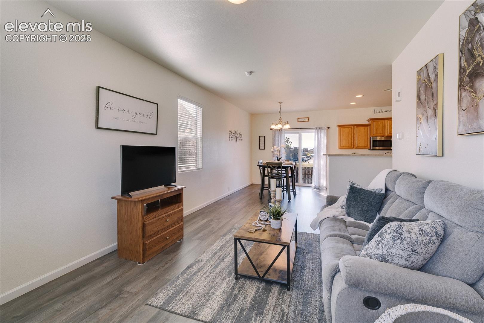 Wood-finish flooring throughout, with a dining area featuring a pendant light fixture and sliding glass door
