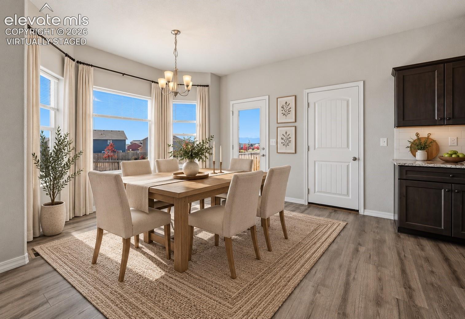Virtually Staged Bay window featuring multiple panels, dark wood-finish cabinetry with stone-surfaced countertops, wood-finish flooring, and a multi-arm chandelier
