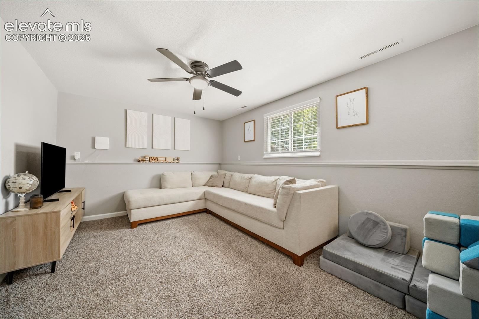 Recessed window with blinds, ceiling fan, carpeted flooring, and a chair rail molding detail