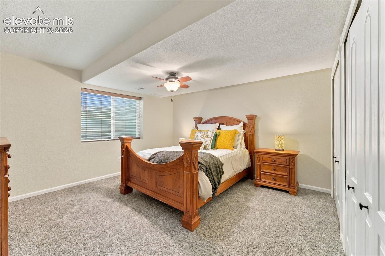Neutral-toned interior featuring wall-to-wall carpeting, ceiling fan with light fixture, and floor-to-ceiling closet doors