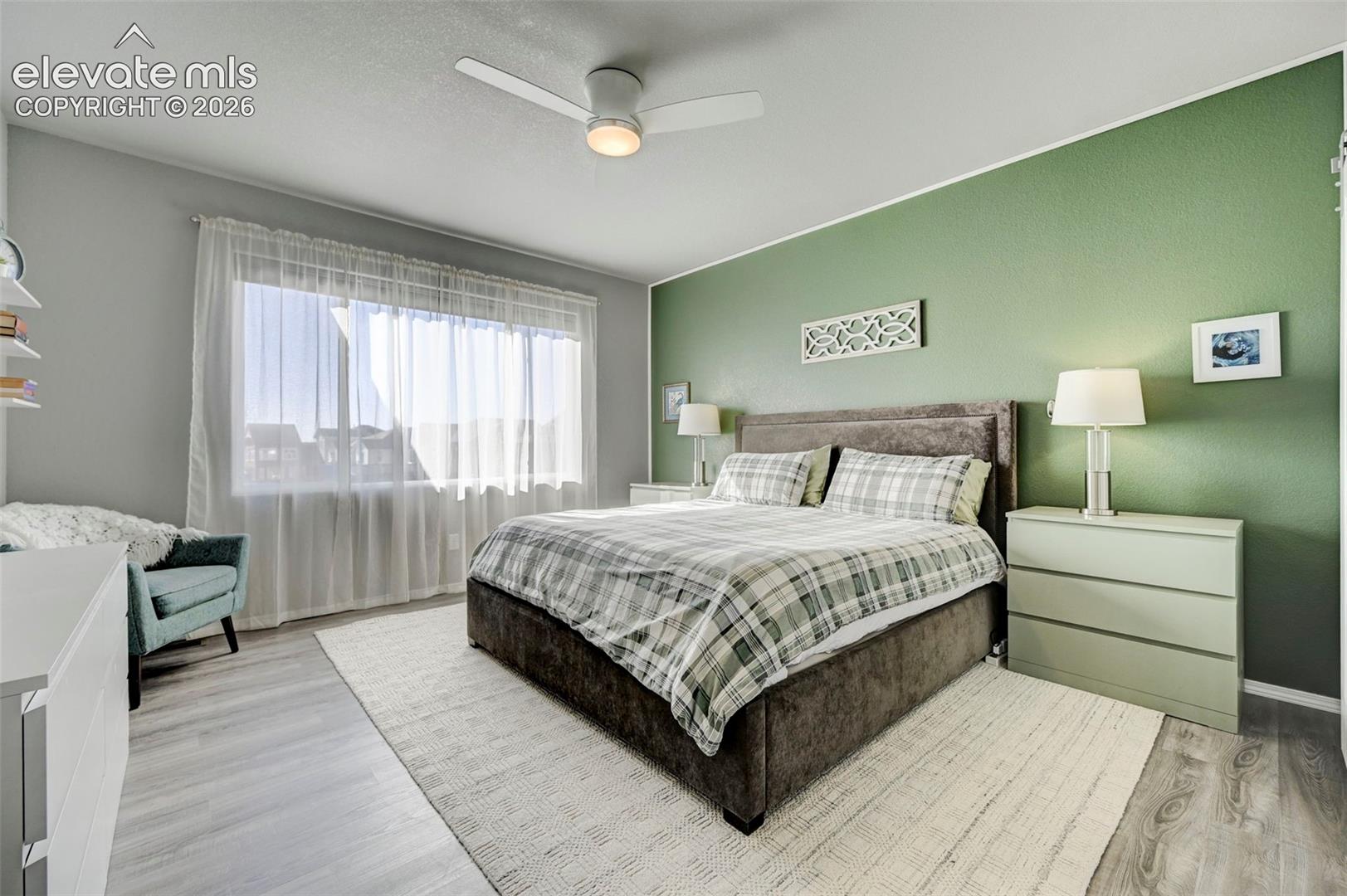 Spacious room featuring wood-finish flooring, a contemporary ceiling fan with integrated lighting, and a prominent window