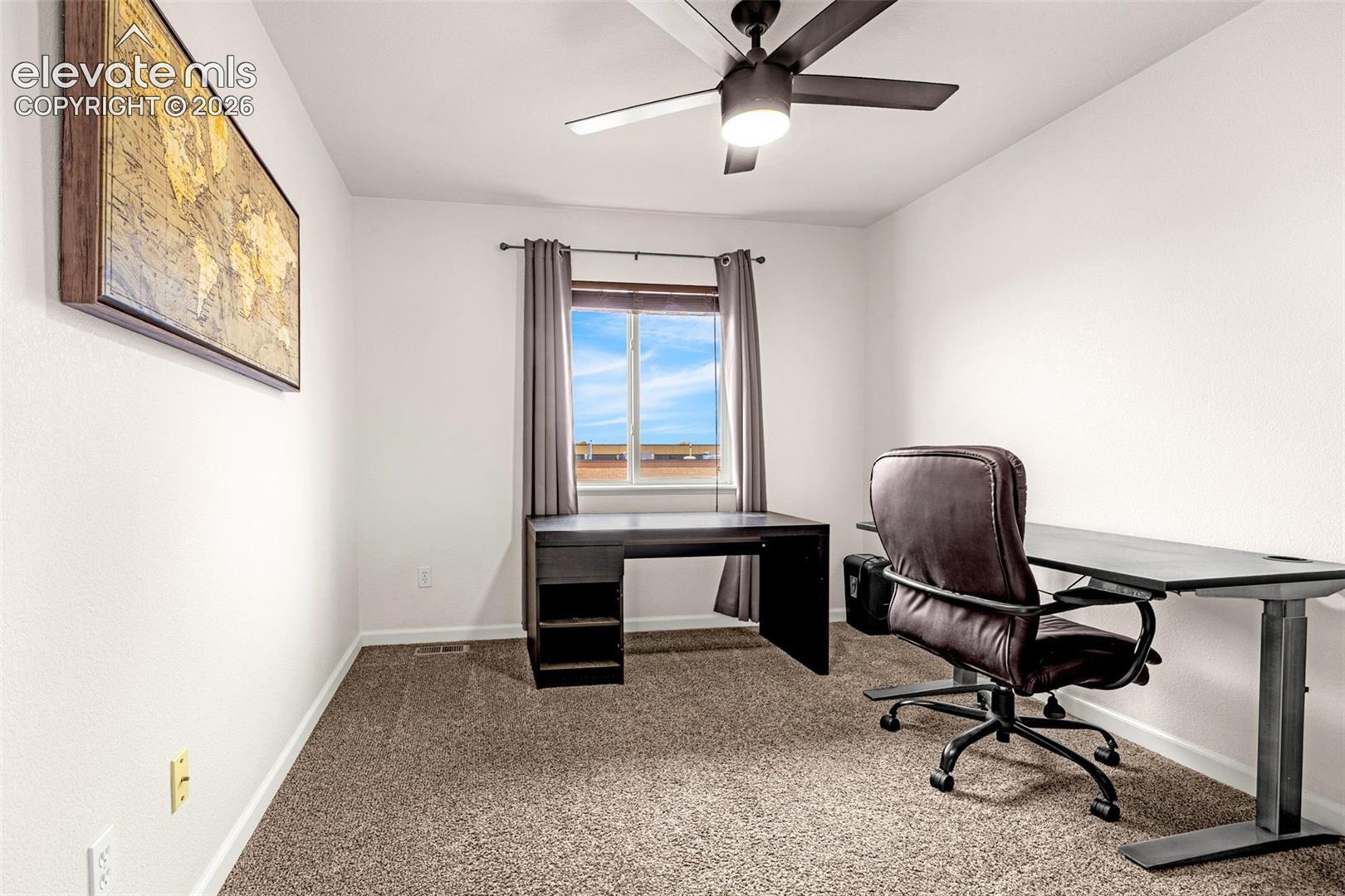 Room featuring neutral-toned carpeting, a central ceiling fan with integrated lighting, and a single-pane window