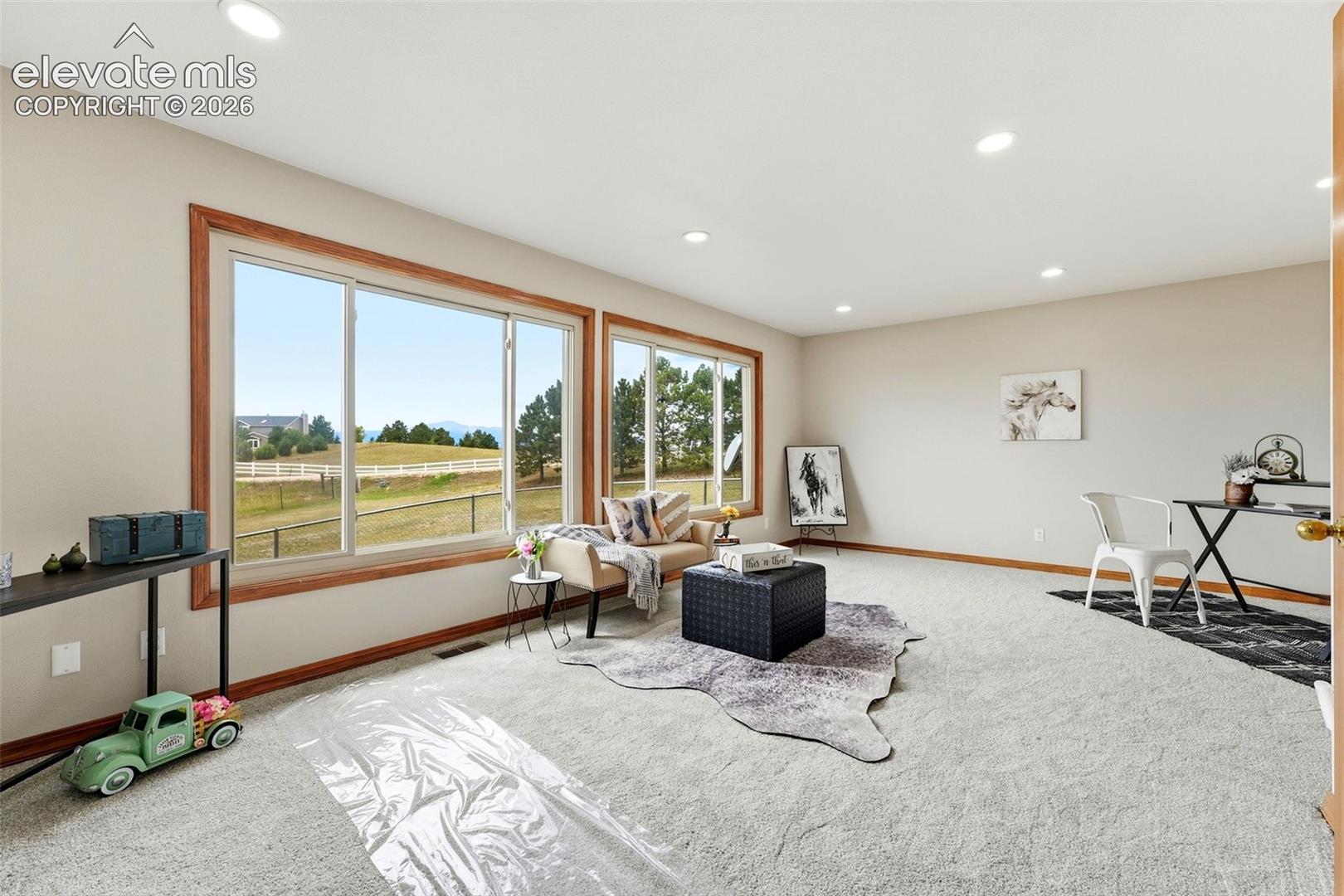 Expansive room featuring multiple windows with wood trim, recessed lighting, and neutral carpeting