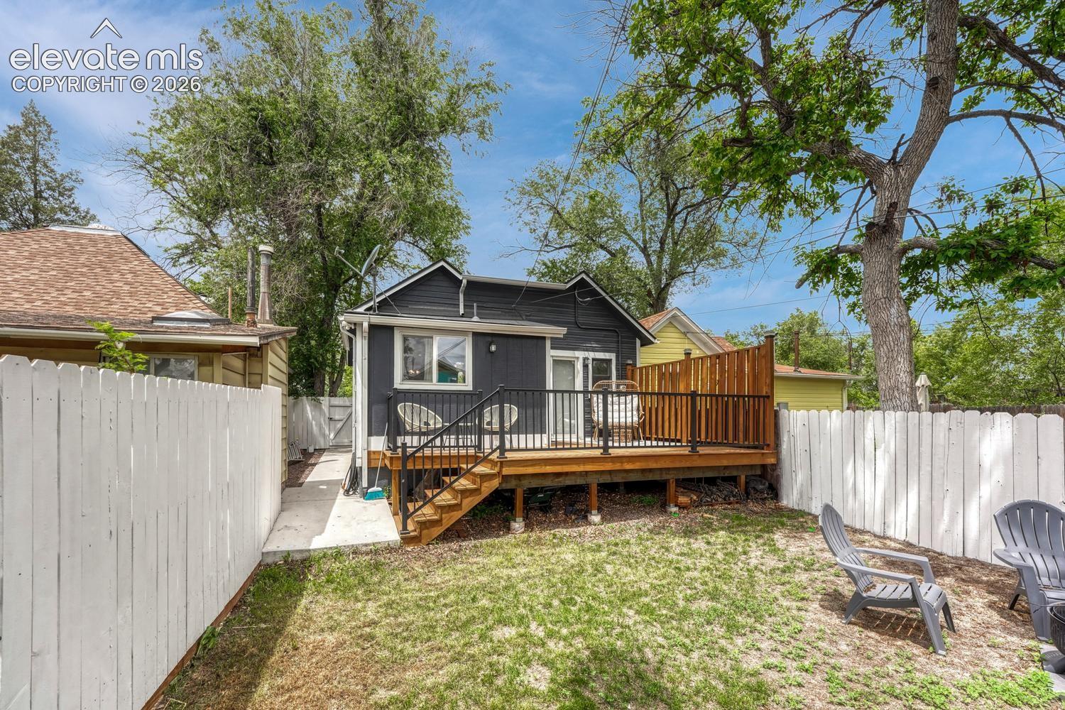 Rear exterior featuring a spacious wood deck with black metal railings and a privacy screen