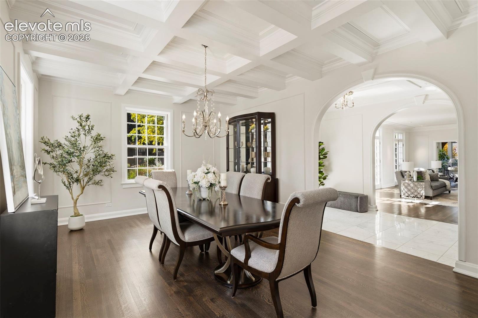 Coffered ceiling, dark-toned wood-finish flooring, architectural arched openings, wall molding, and multi-pane windows