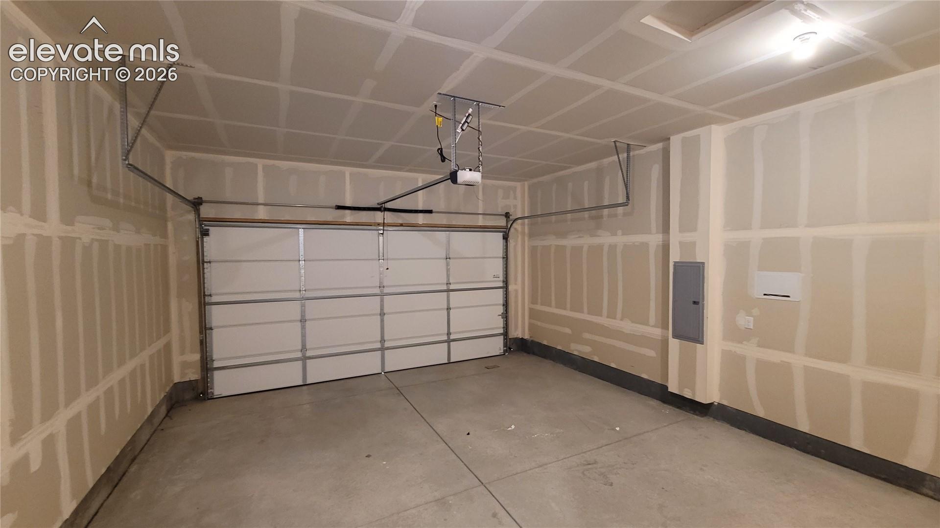 Two-car garage featuring a sectional overhead door, concrete flooring, and an automated door opener system