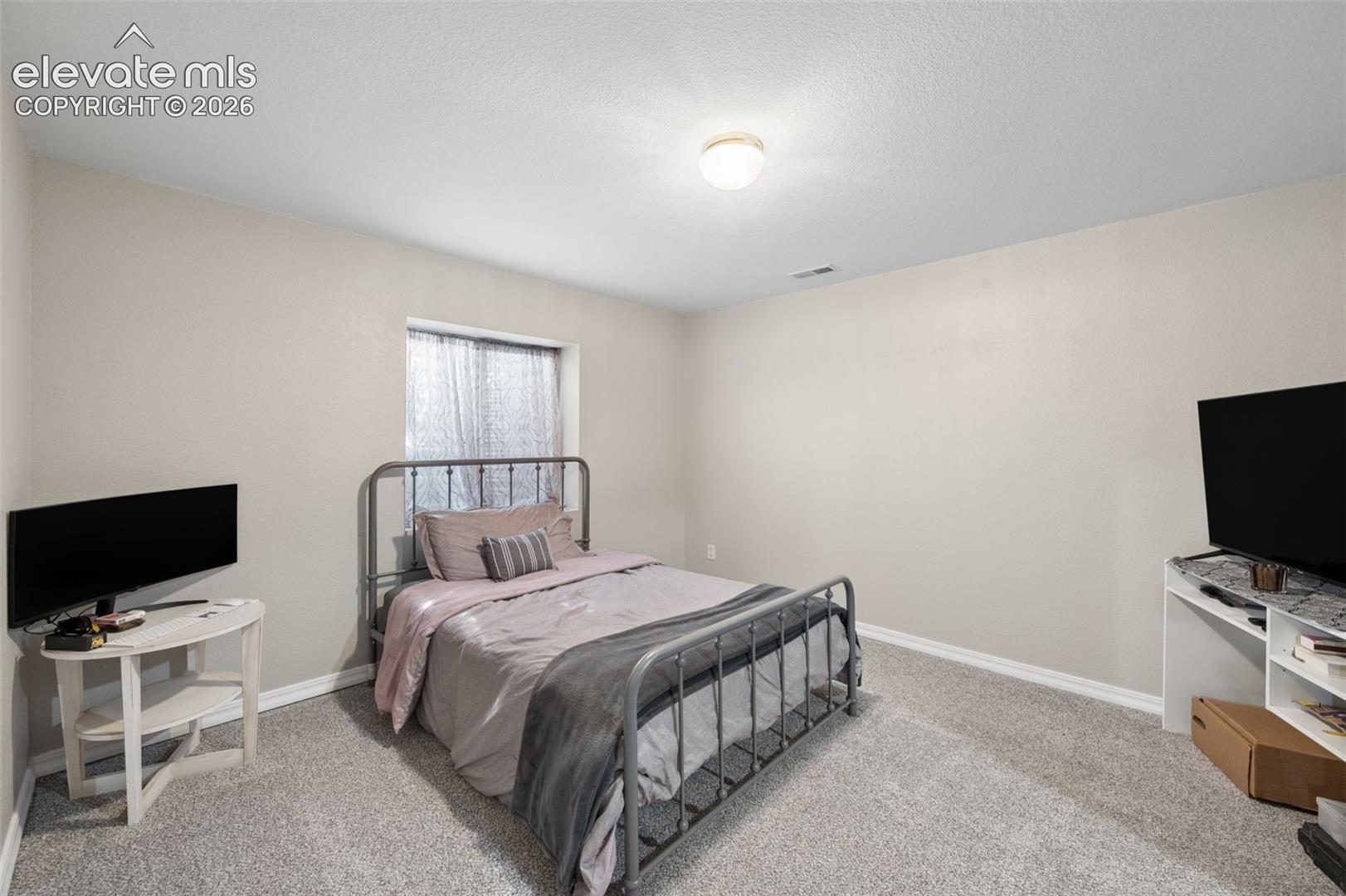 Neutral-toned interior space featuring wall-to-wall carpeting, a single-panel window, and a central flush-mount ceiling light fixture