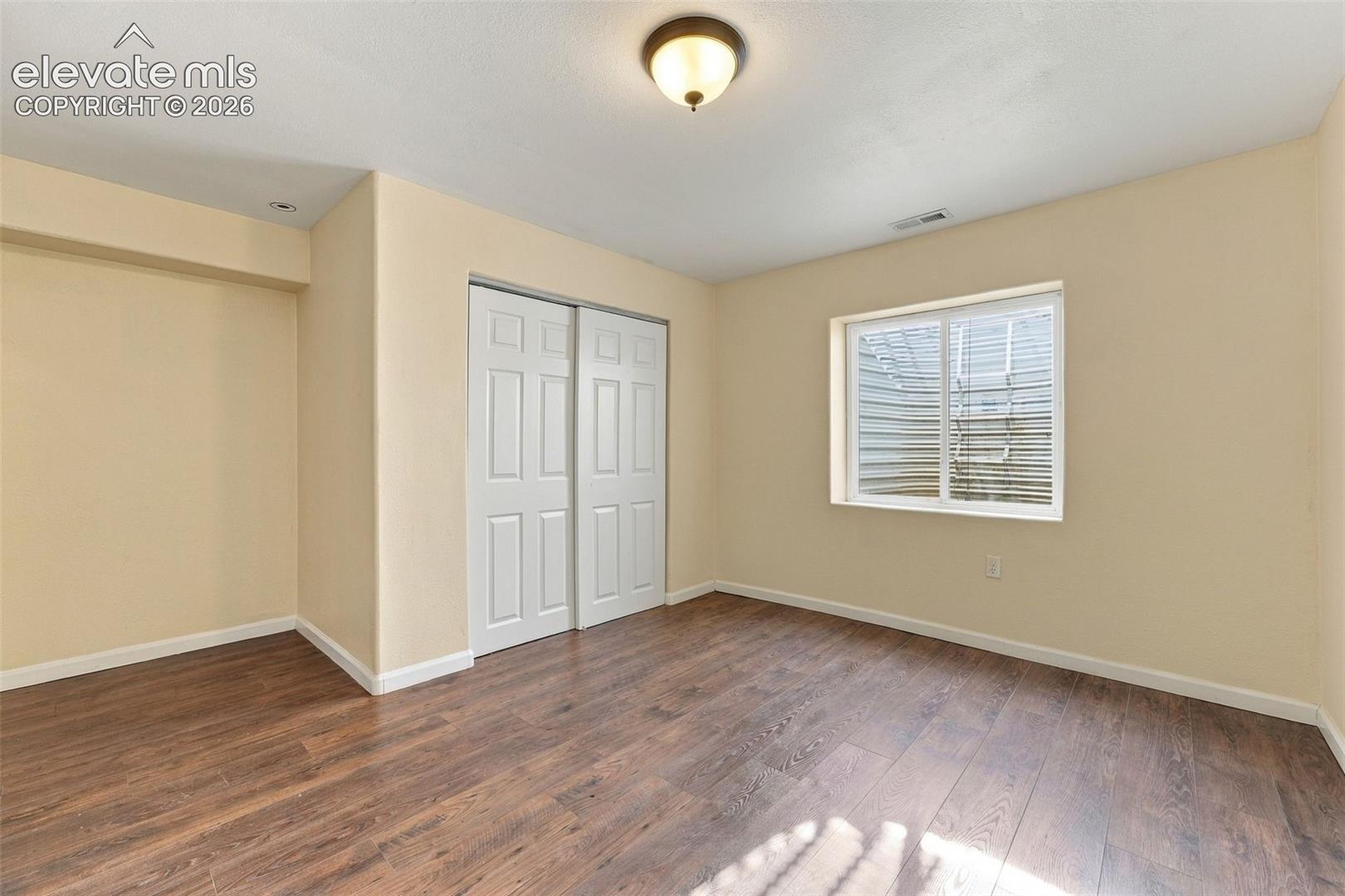 Wood-finish flooring, dual-panel sliding closet doors, and a double-pane window with an egress well