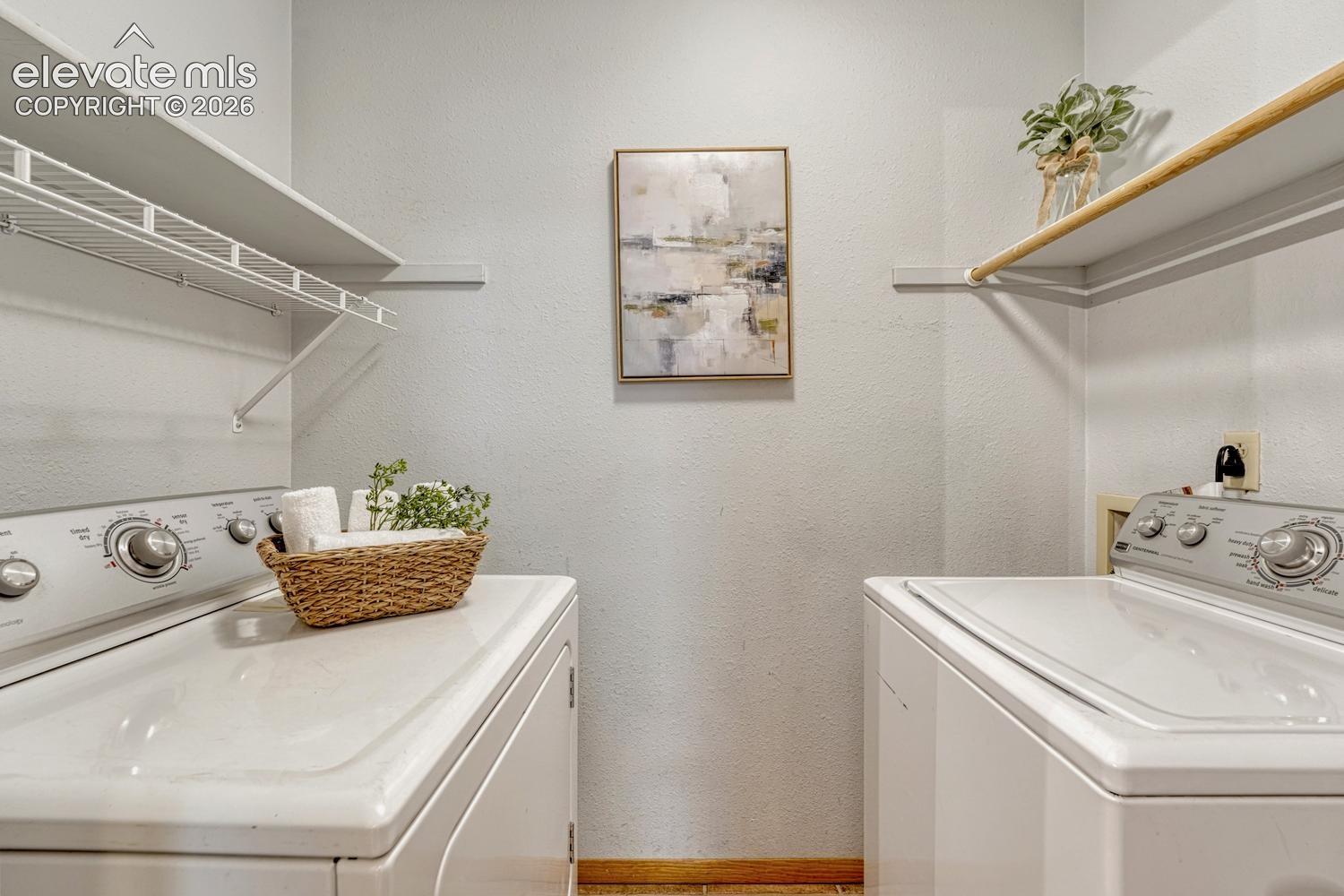 Laundry room with tile flooring, built in shelves, and washer/dryer included.