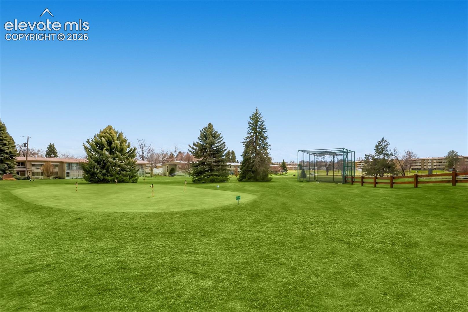 Expansive grounds featuring a manicured lawn with mature evergreen and deciduous trees, fencing, and a pergola structure
