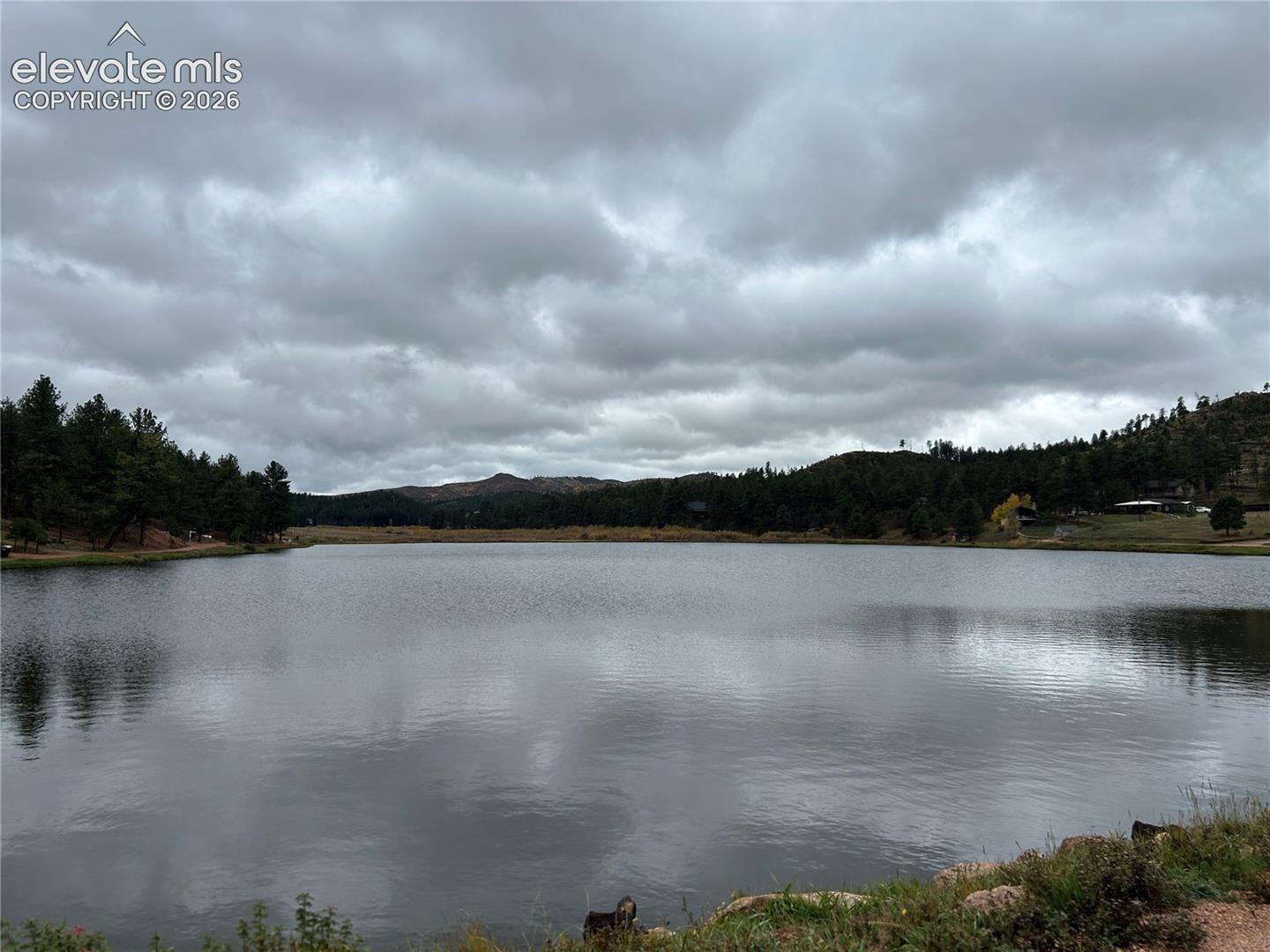 Natural lake with coniferous forest borders and mountainous terrain
