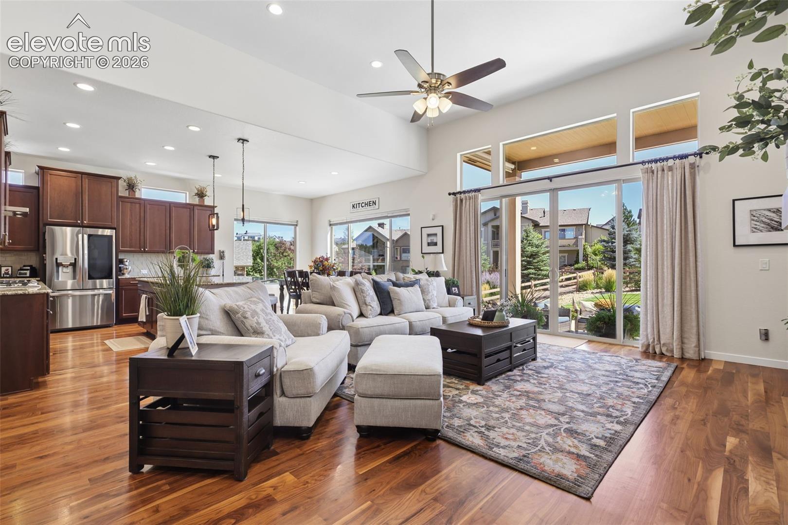 Vaulted ceiling with recessed lighting, wood-finish flooring, full-height sliding glass doors, and a ceiling fan