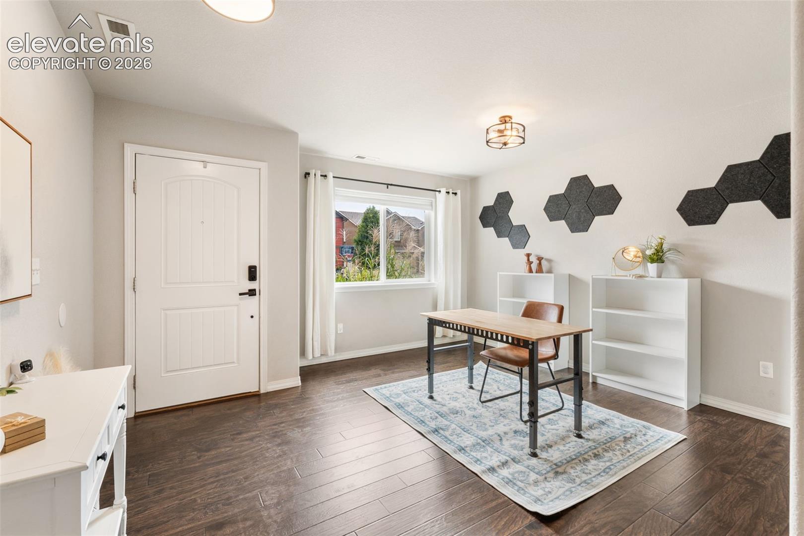 Entryway with wood-finish flooring, a white paneled door, and a multi-pane window