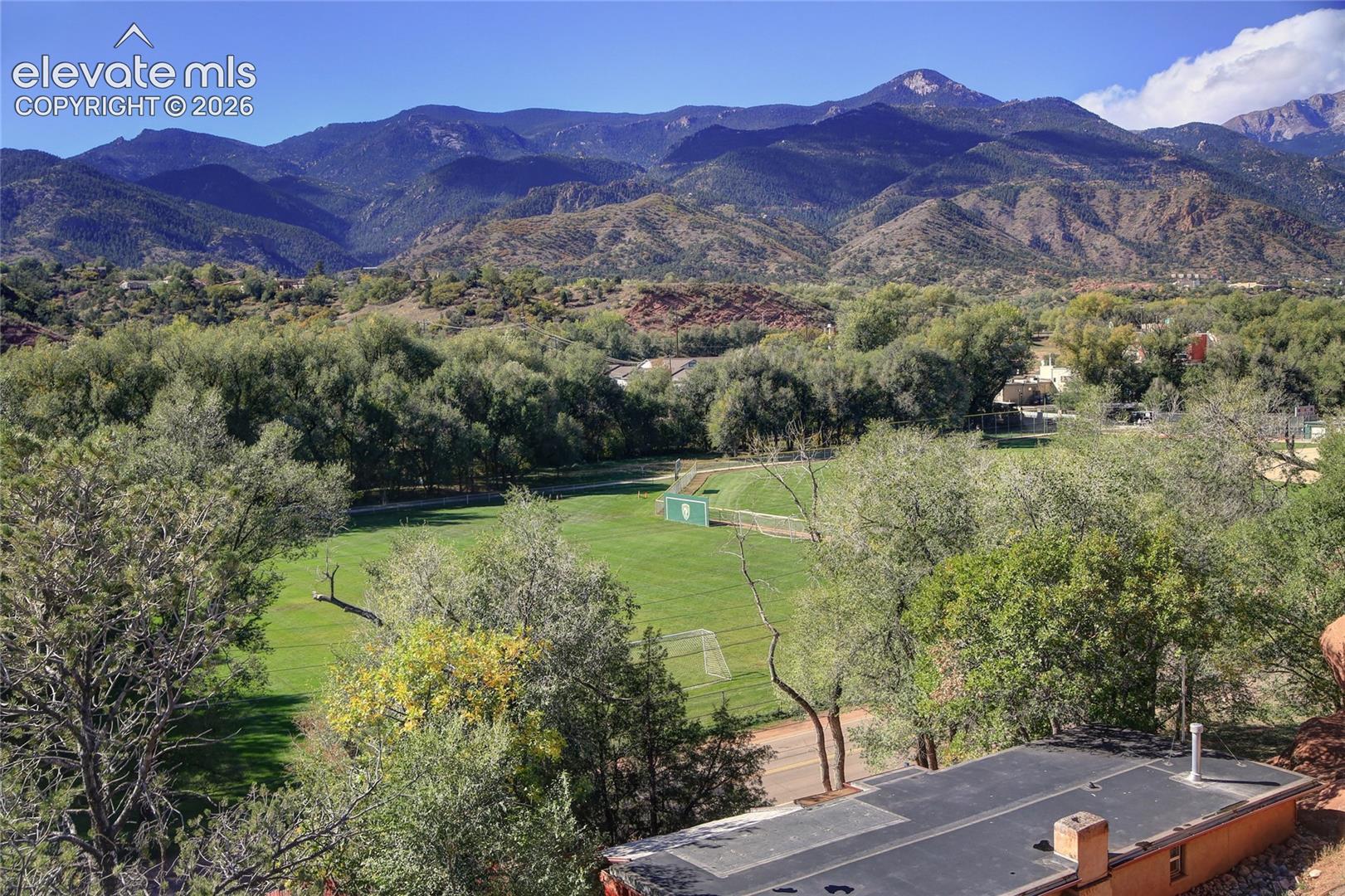 Expansive mountain range backdrop featuring mature trees and a manicured grass field