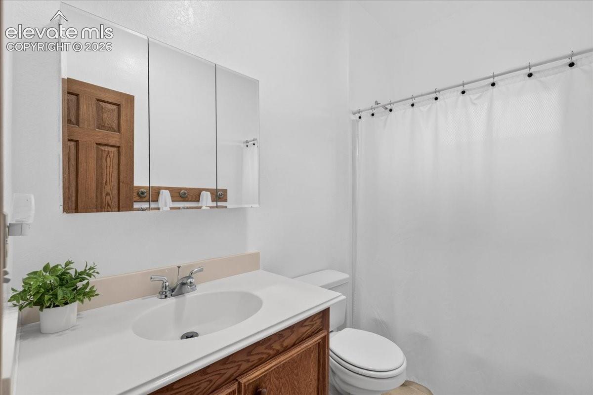 Bathroom featuring a wood-finish vanity with a white countertop and oval under-mount sink, three-panel medicine cabinet, and a chrome faucet