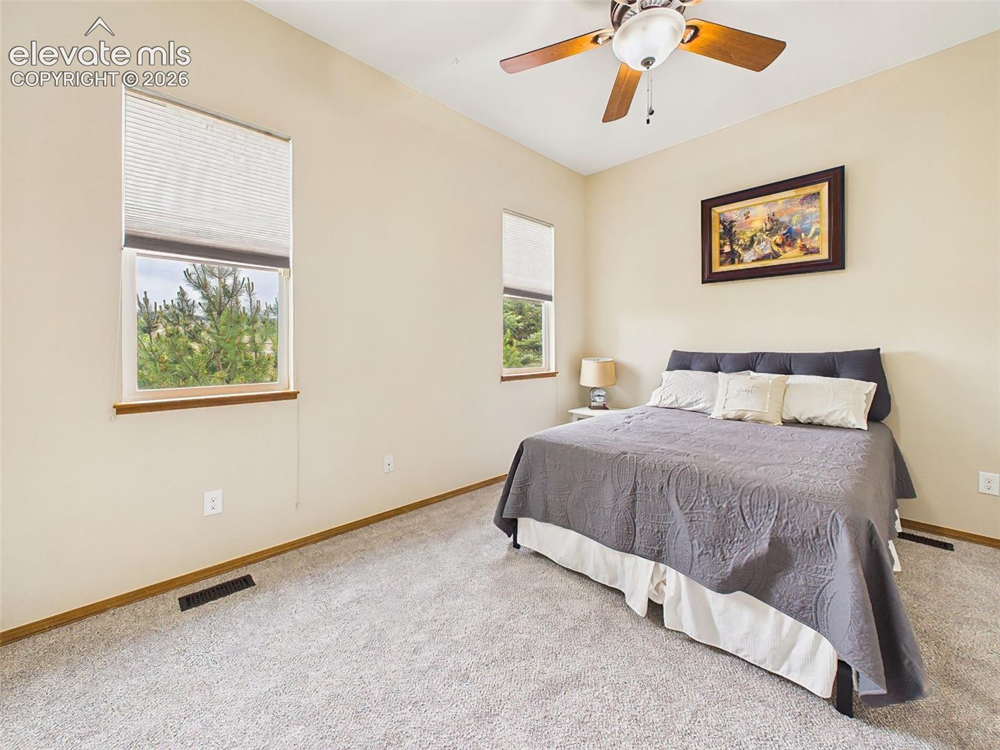 Bright main level bedroom featuring neutral tones, large windows, and a cozy, inviting layout.