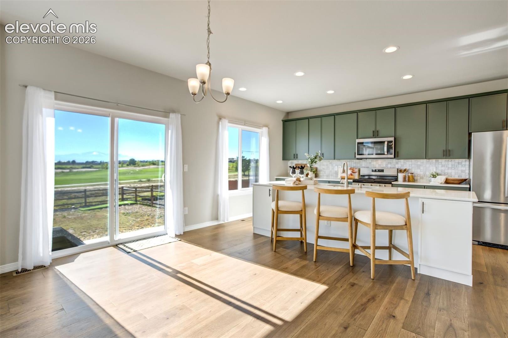Open-concept living space with wood-finish flooring, a sliding glass door, modern chandelier, and recessed lighting