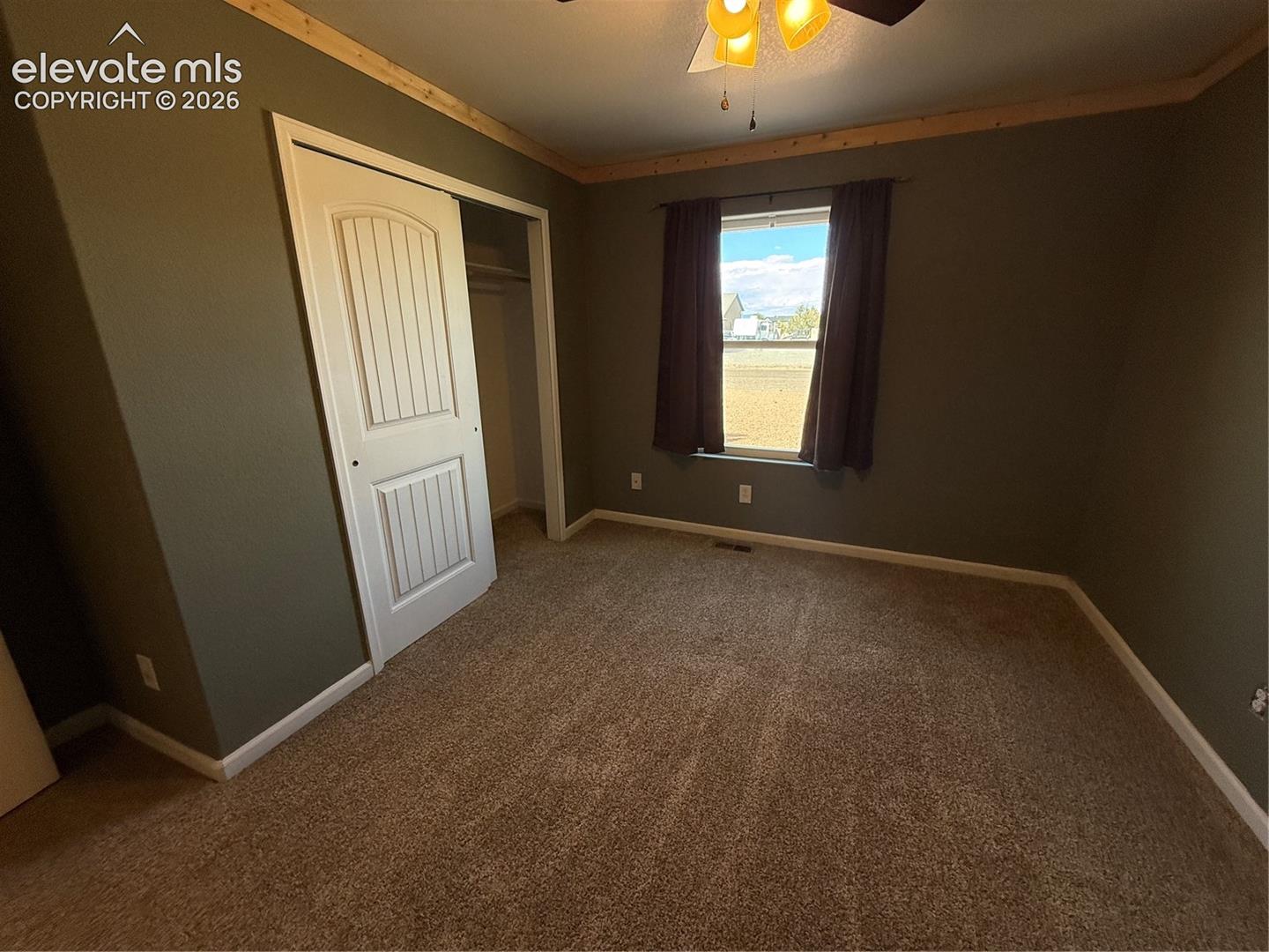 Room featuring neutral carpeting, a dual-panel interior closet door, and natural wood crown molding