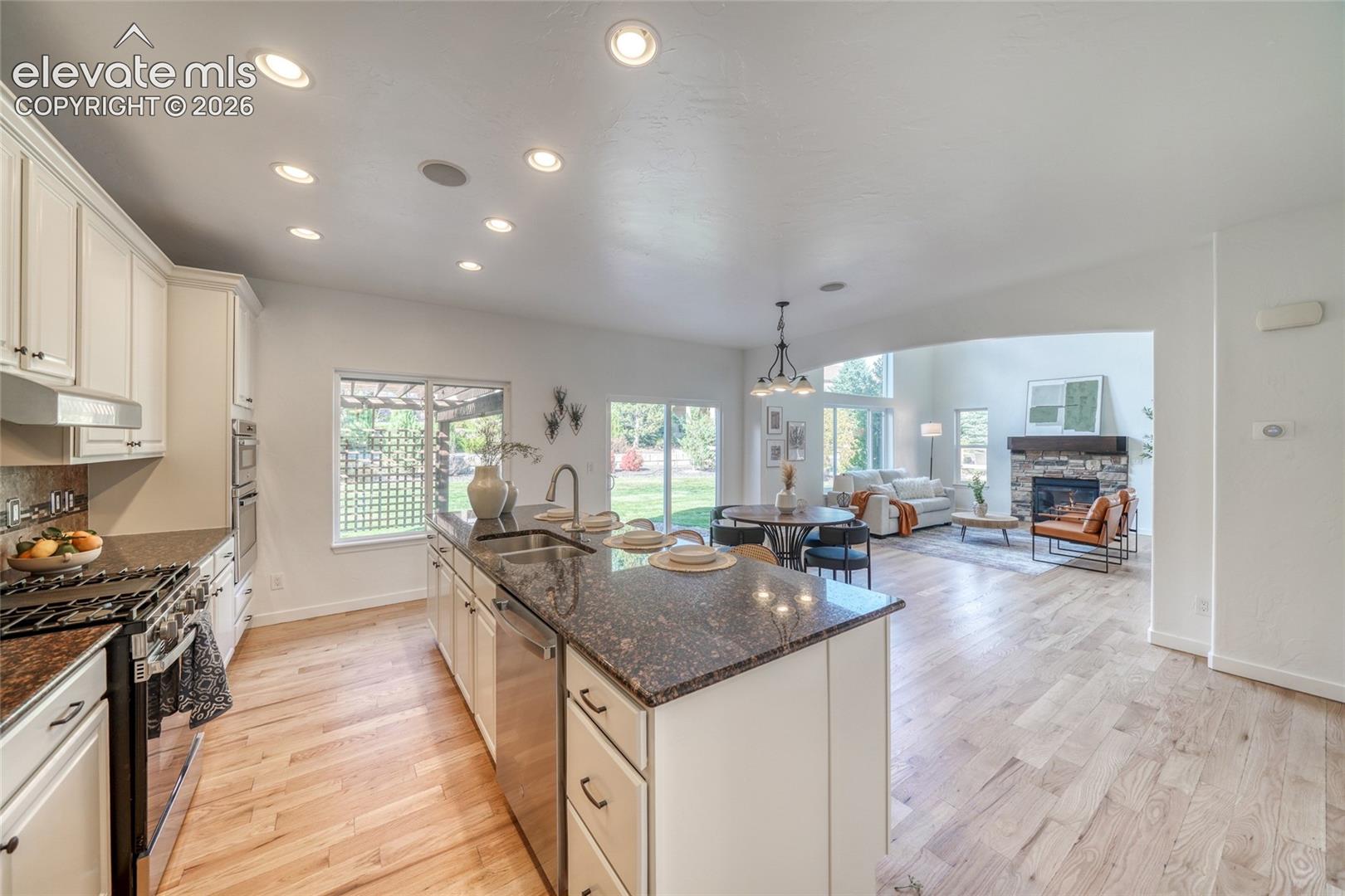 Open-concept kitchen with light wood-finish flooring, recessed lighting, and a kitchen island featuring a granite countertop