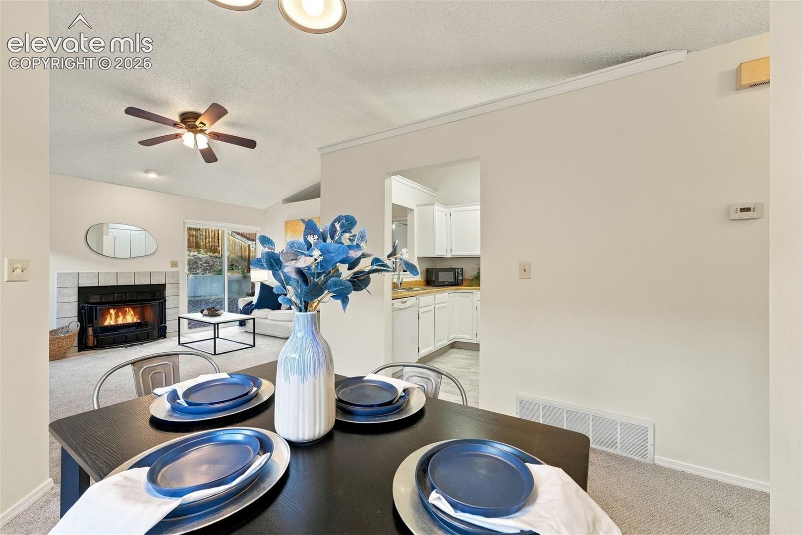 Vaulted ceilings, fireplace with tile surround, sliding glass door, and white cabinetry