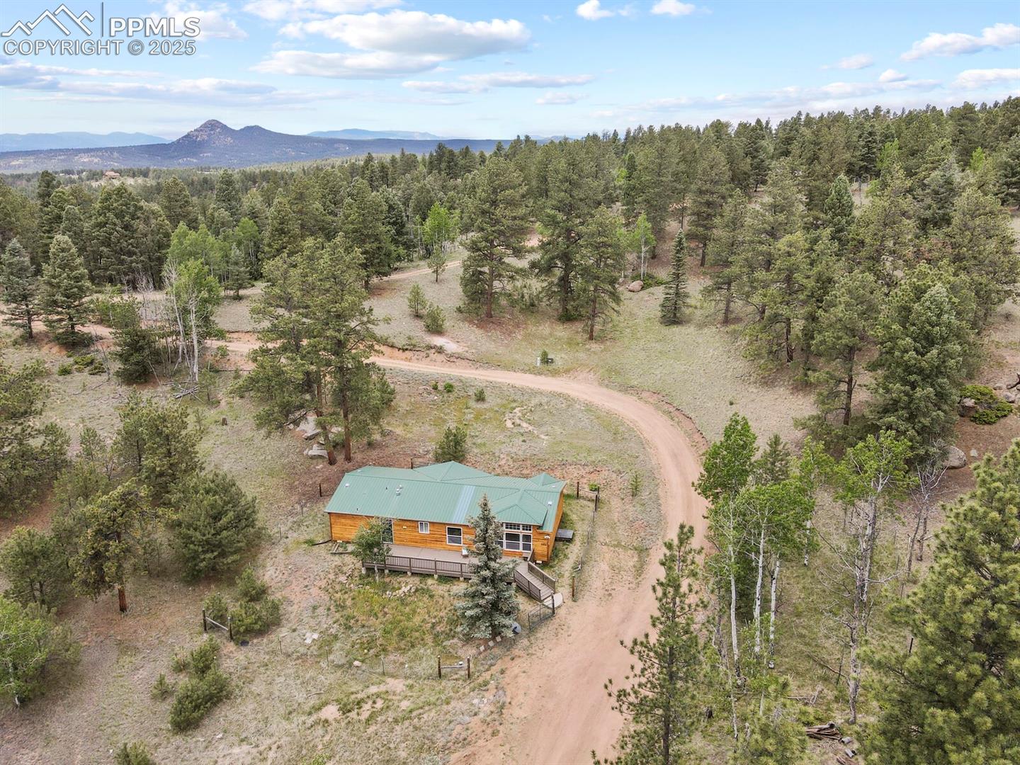 View from above of property featuring a mountain backdrop and a heavily wooded area