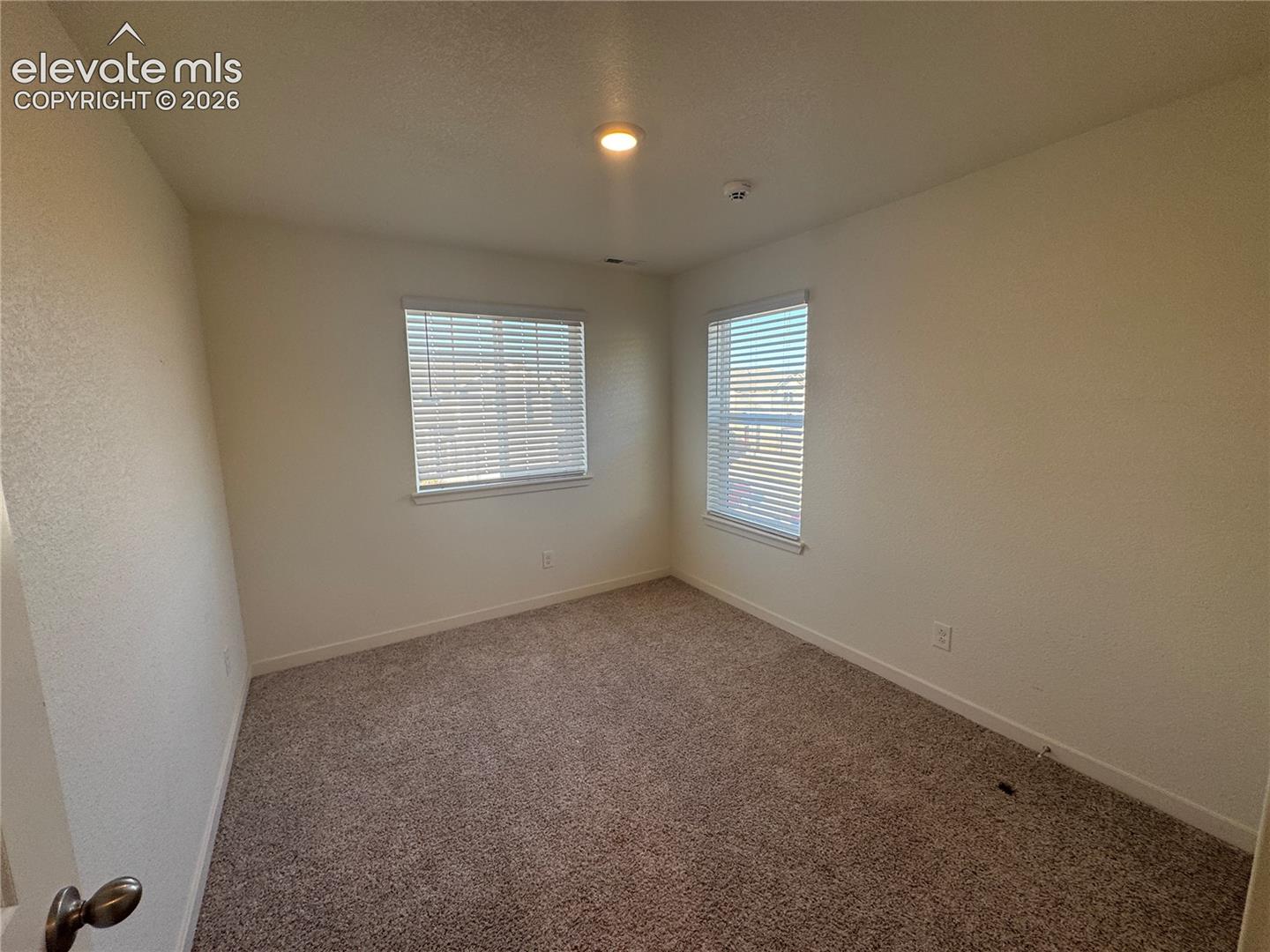 Neutral-toned carpeted flooring, dual windows with integrated blinds, and recessed ceiling lighting