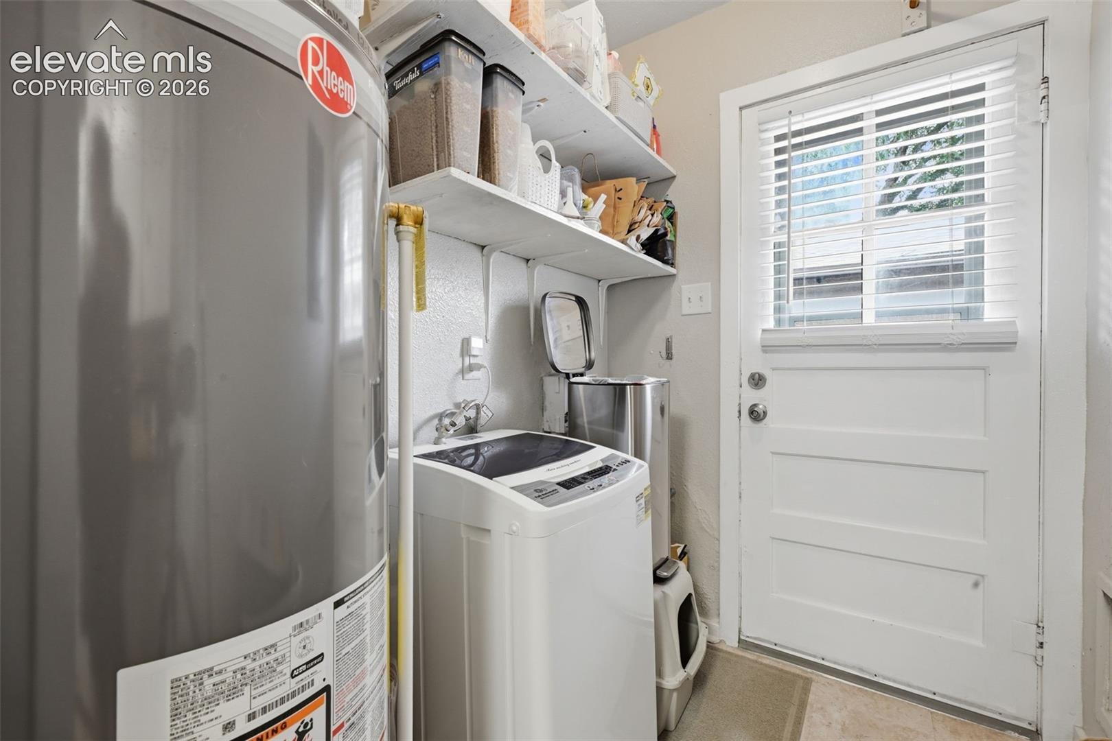 Laundry area featuring built-in shelving and a white panel door with a window