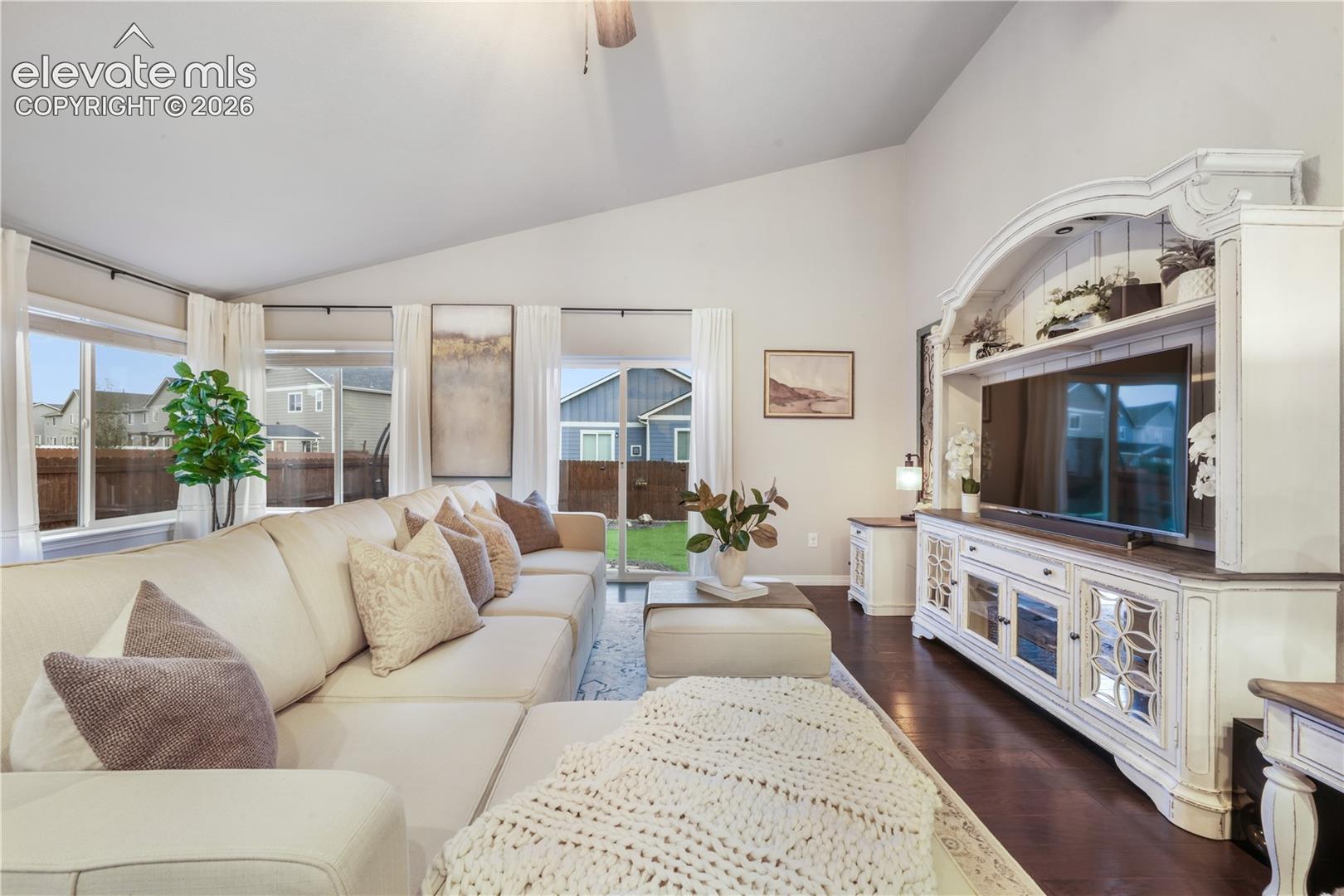 Vaulted ceilings, large windows, dark wood-finish flooring, built-in entertainment center, and a sliding glass door