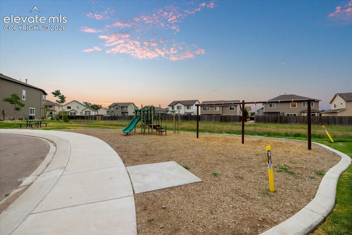 Community playground featuring a slide, swing set, and a surrounding paved pathway